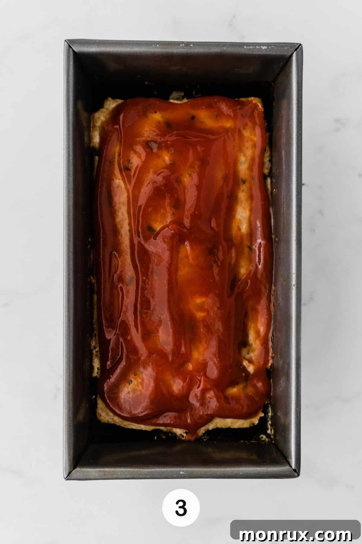 The chicken meatloaf mixture pressed firmly into a loaf pan before initial baking.