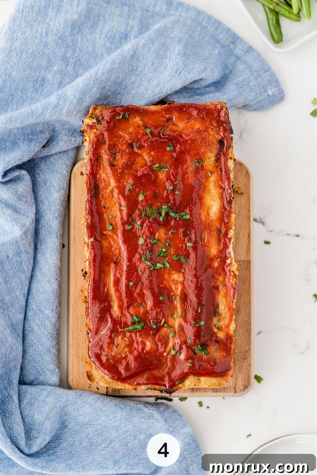 A perfectly cooked chicken meatloaf, glazed with ketchup, resting in the loaf pan after baking.