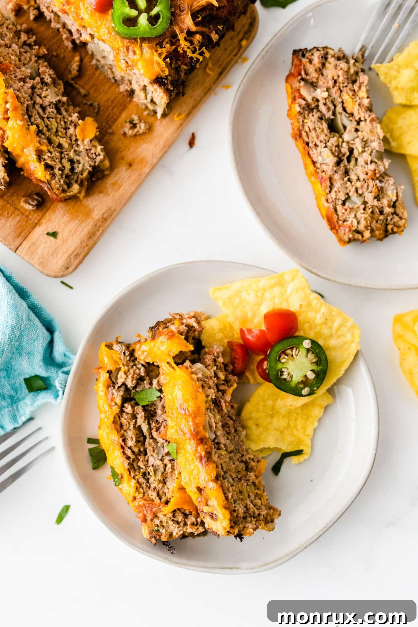 Cooked taco meatloaf sliced and served on two plates with forks, garnished with cilantro.