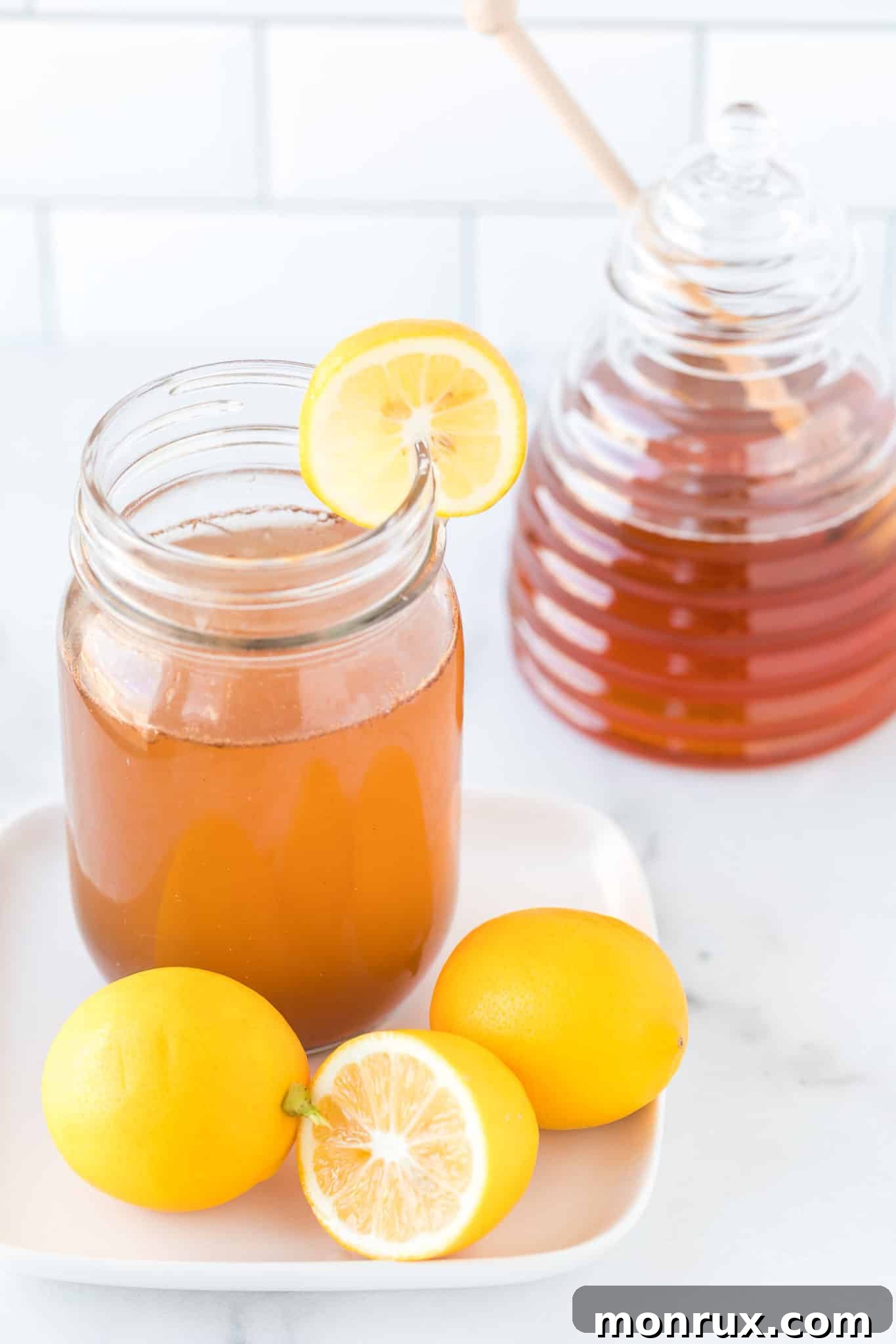 A cozy mug filled with freshly prepared Lemon Cinnamon Water, garnished with bright lemon slices and a cinnamon stick, resting on a plate.