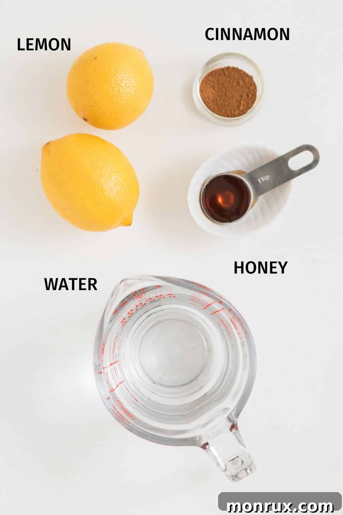 Artfully arranged ingredients for lemon cinnamon water, including fresh lemons, ground cinnamon, and a jar of honey, on a rustic wooden table.