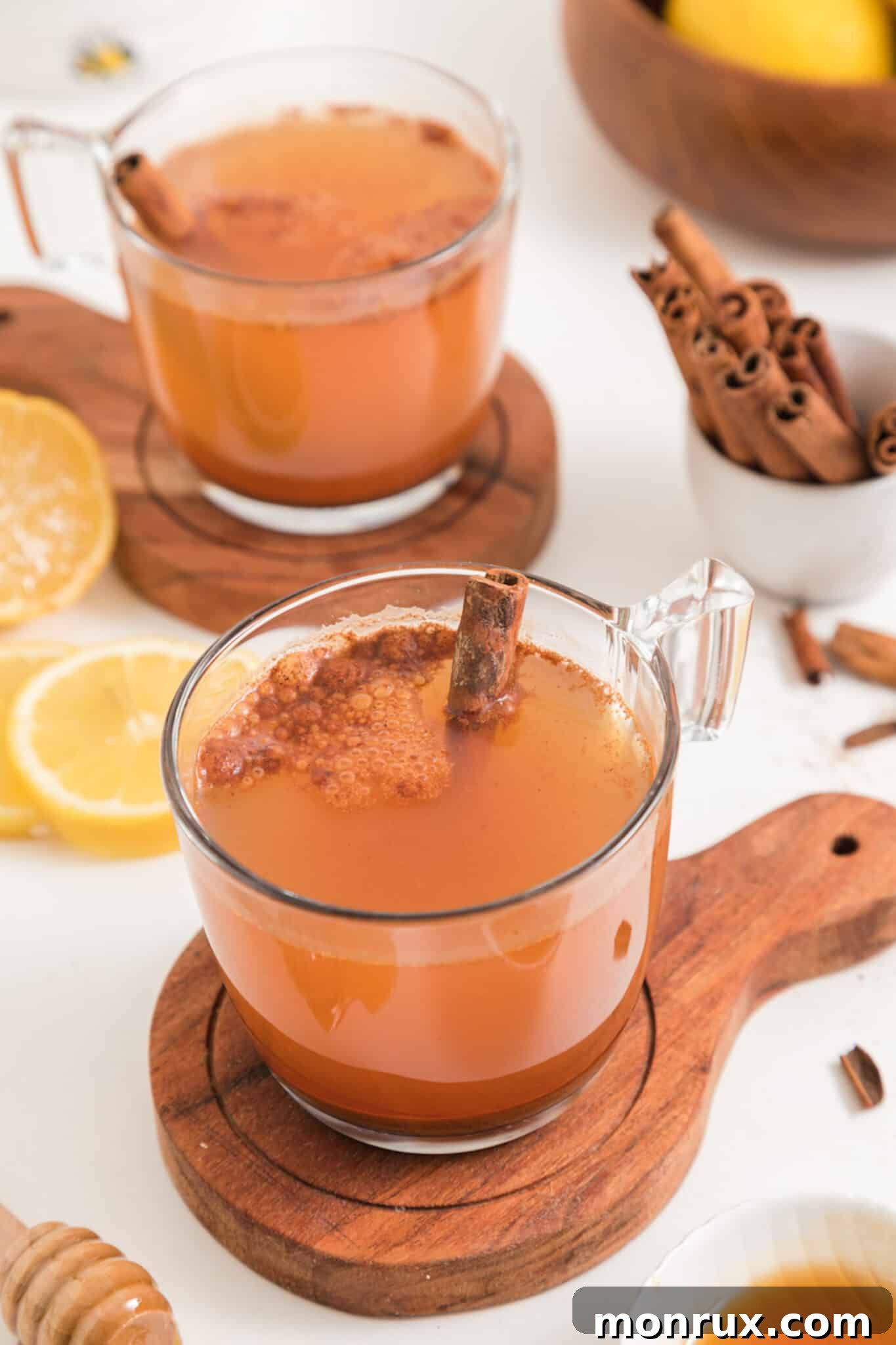 Two mugs filled with inviting lemon water, each featuring a sprinkle of ground cinnamon on top, ready to be enjoyed.
