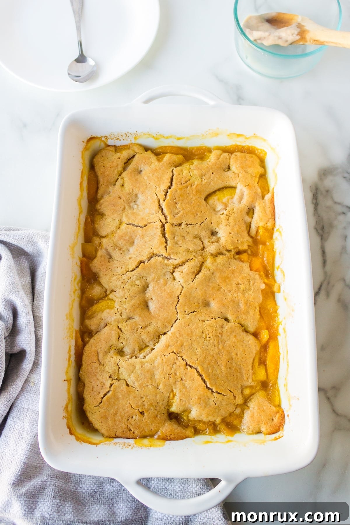 Step three: spreading the crumble topping over the peach filling in the baking pan.