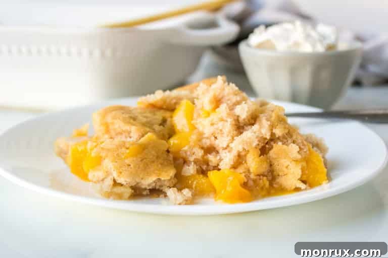 A plate of peach cobbler with a bowl of whipped cream behind it.