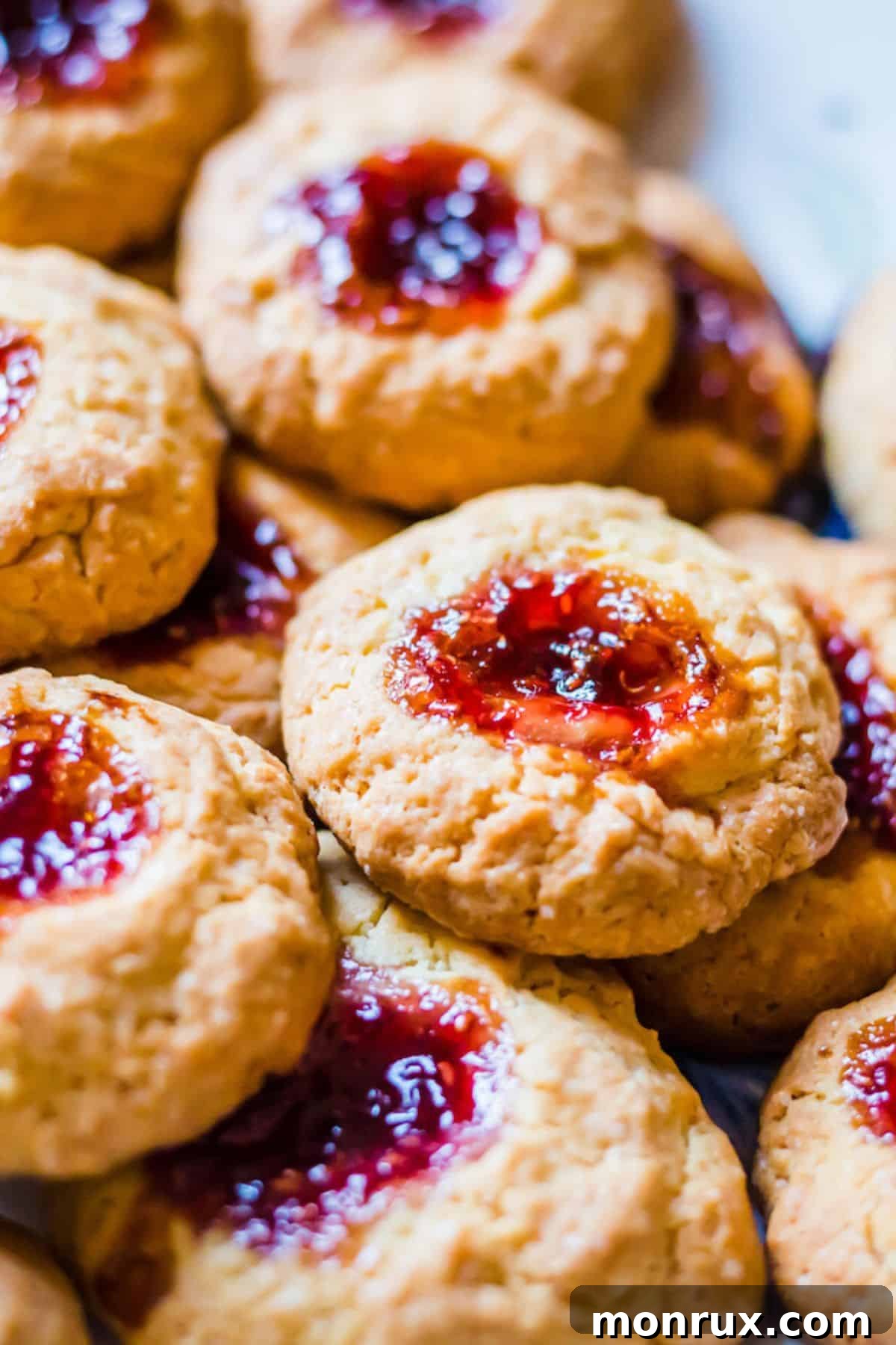 Stack of perfectly baked gluten-free thumbprint cookies, showcasing their golden edges and vibrant jam centers, ready to be enjoyed.