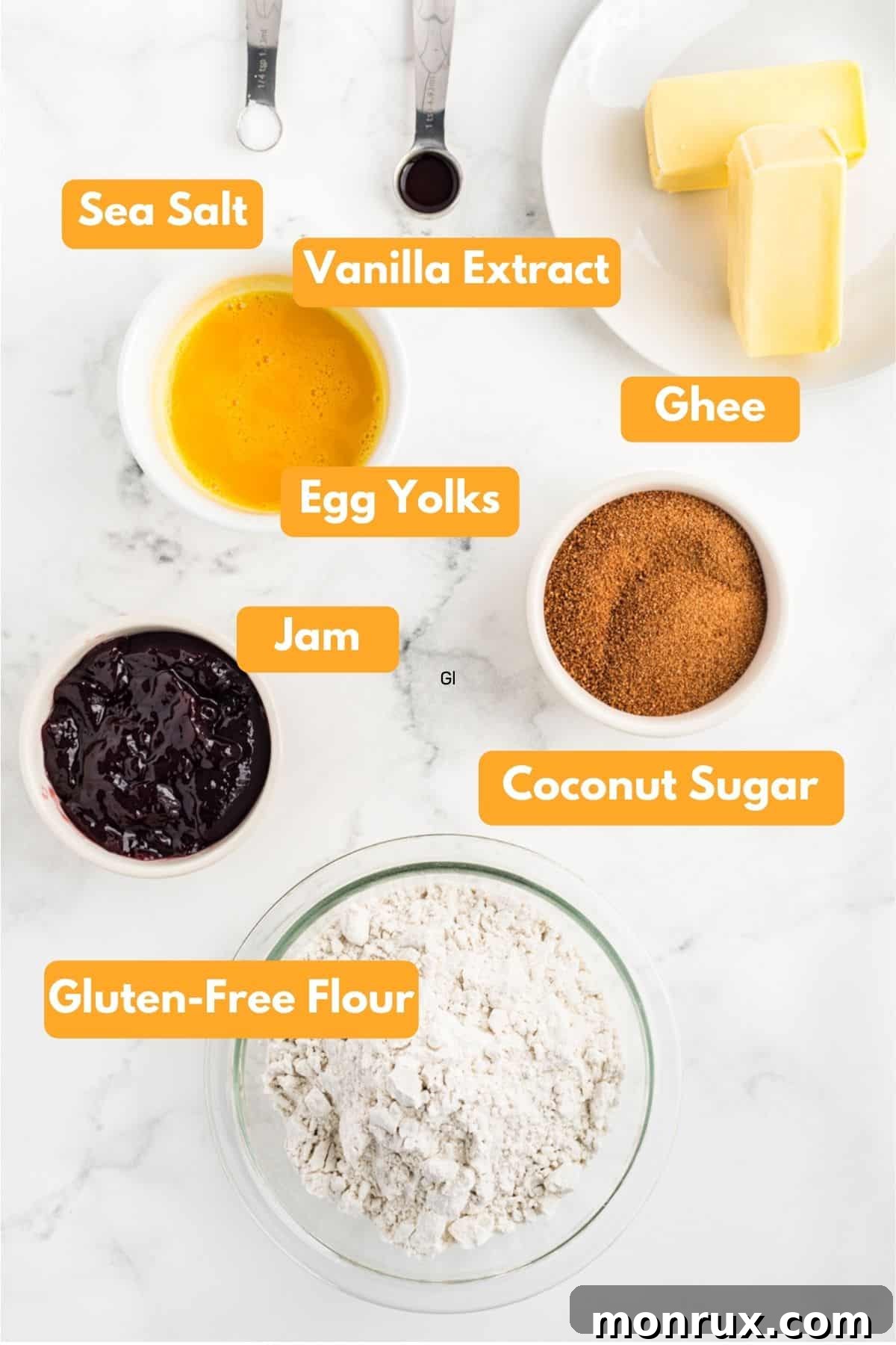 A curated selection of fresh ingredients laid out, including gluten-free flour, coconut sugar, ghee, fresh eggs, vanilla extract, and various fruit jams, ready for baking thumbprint cookies.