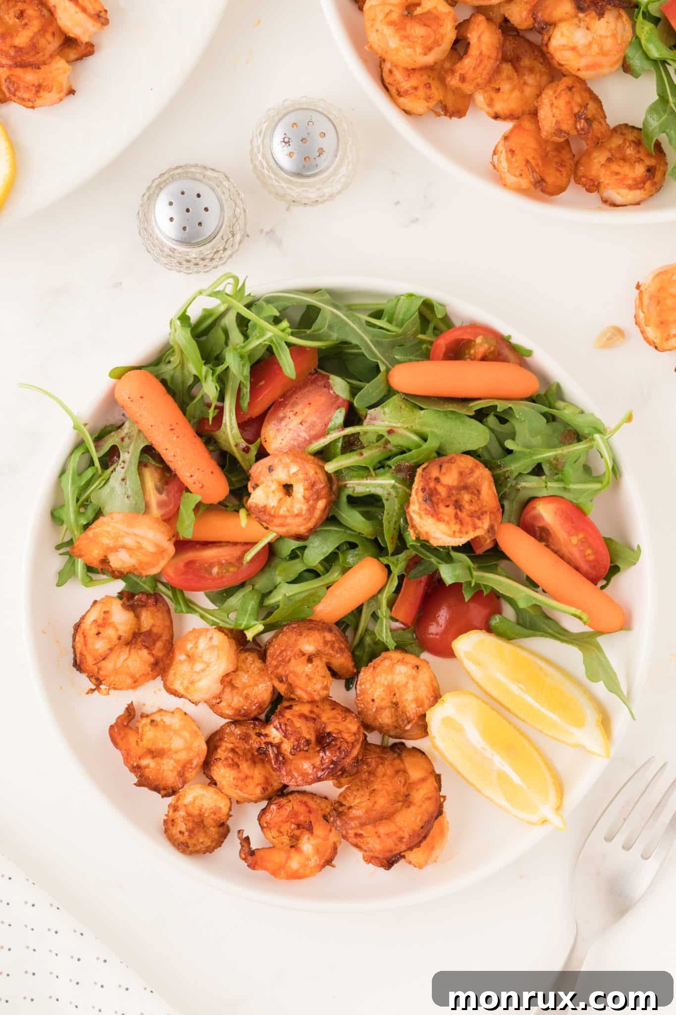 Lemon garlic air fried shrimp with salad on a plate.