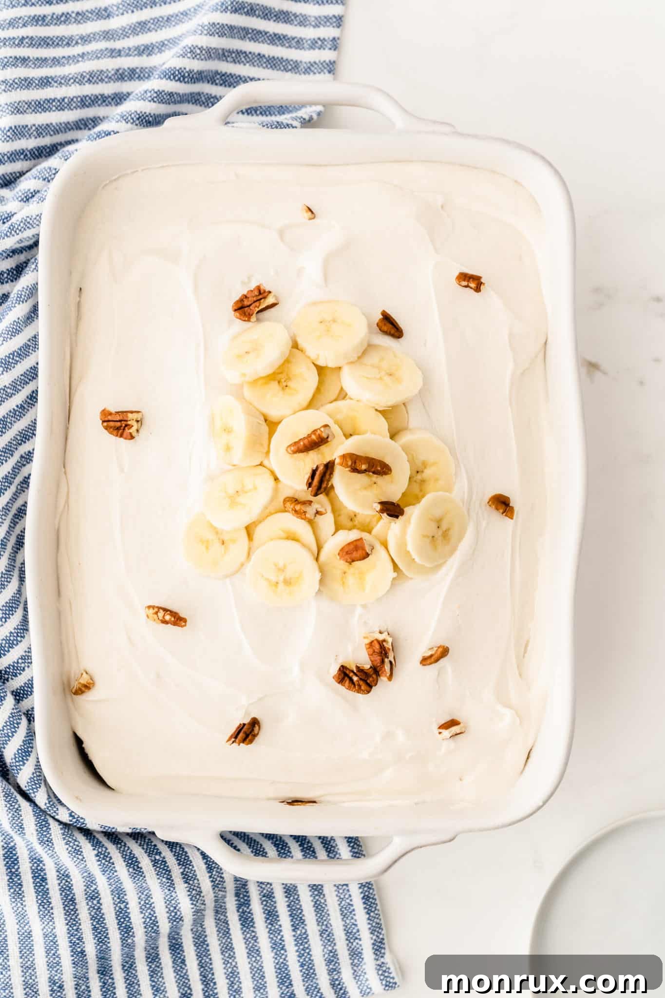 A beautifully frosted gluten-free and dairy-free banana cake, garnished with fresh banana slices on top.