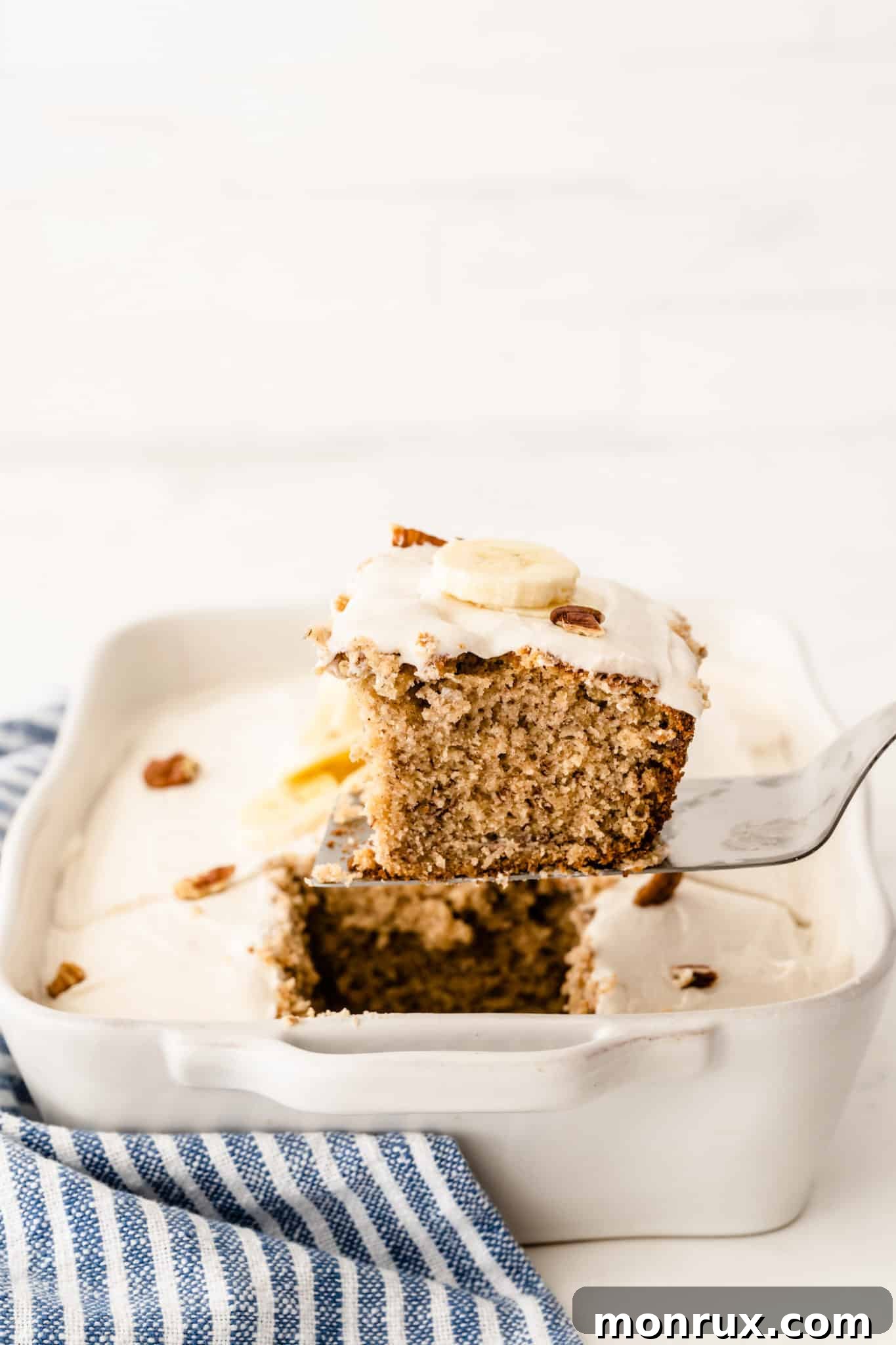 A beautifully cut slice of gluten-free banana cake with a generous layer of vanilla frosting.