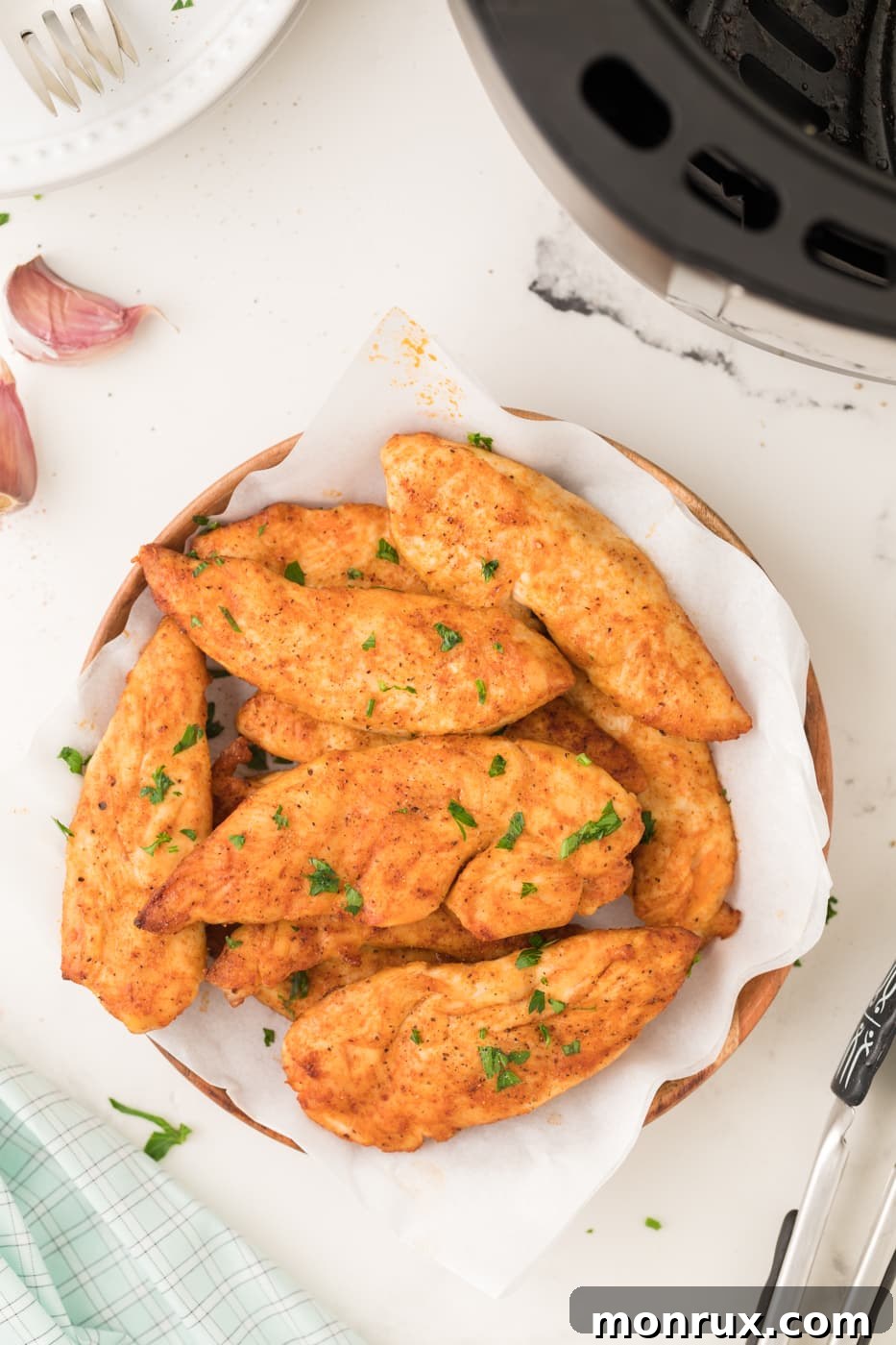 A plate of perfectly seasoned and golden-brown chicken tenders cooked in an air fryer, ready to be served.