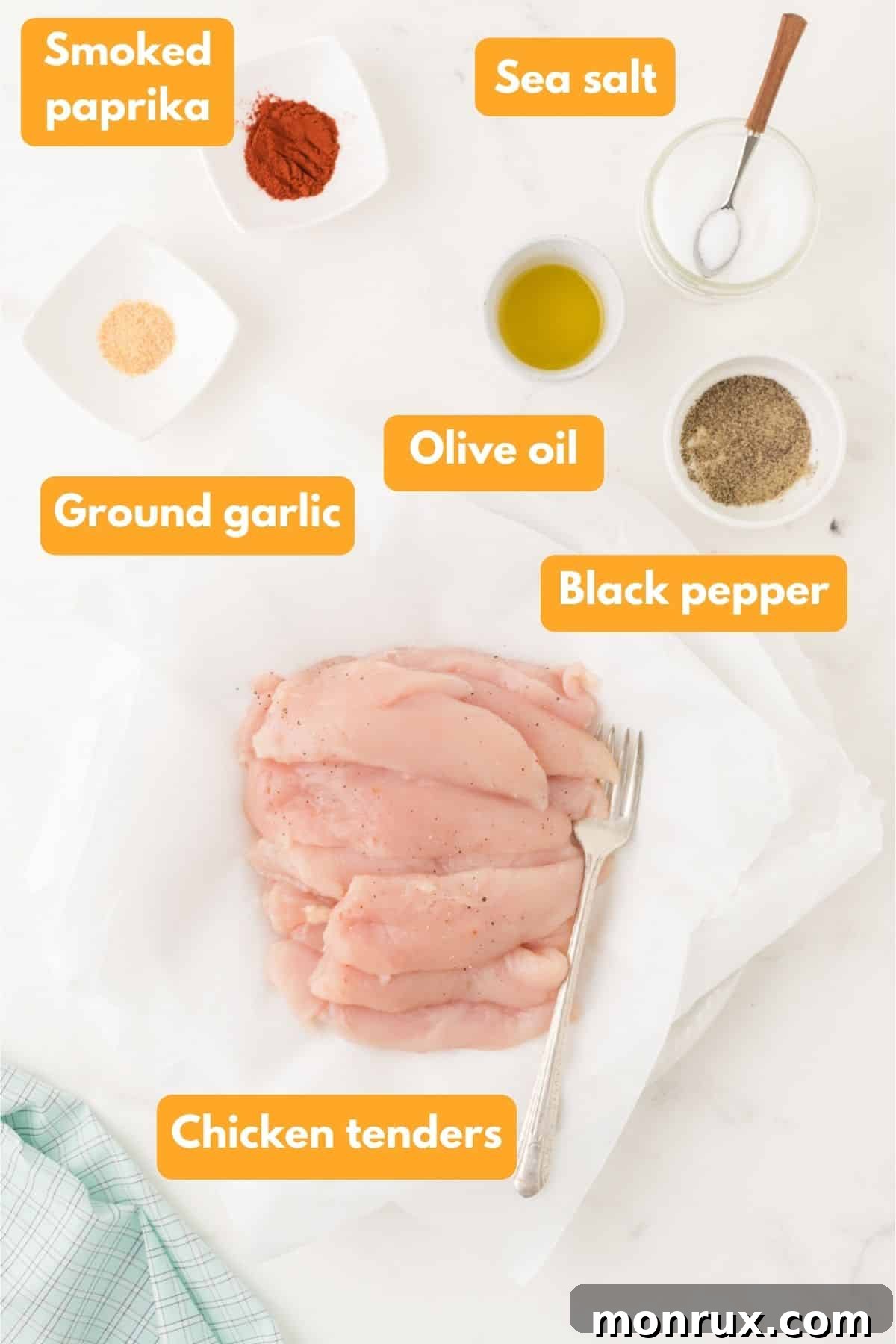 Fresh chicken tenders, olive oil, and various spices laid out on a kitchen counter, ready for air frying.