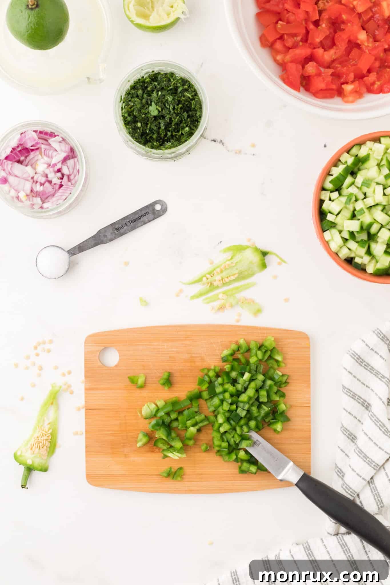 Step one of making cucumber pico de gallo: chopping jalapeno pepper on a cutting board.