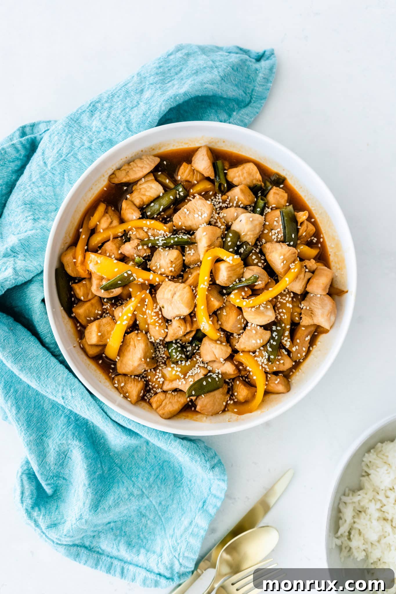 A vibrant bowl of homemade Panda Express Honey Sesame Chicken, featuring tender chicken pieces, crisp bell peppers, and snap peas, garnished with sesame seeds.