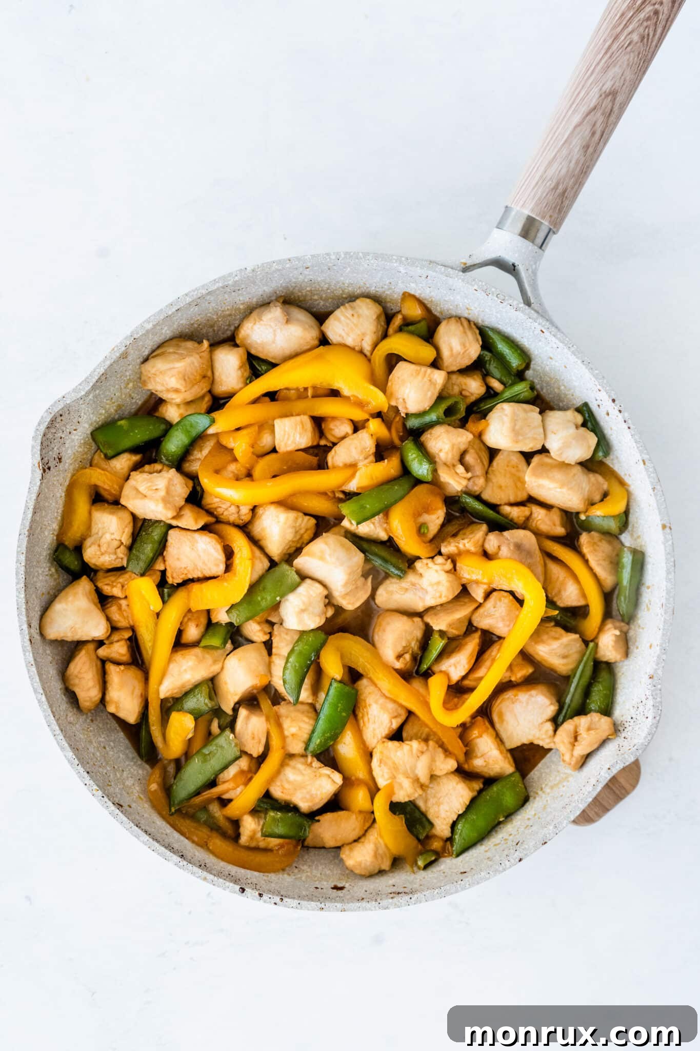The completed honey sesame chicken dish in the pan, with all ingredients cooked and the sauce thickened, ready to be served.