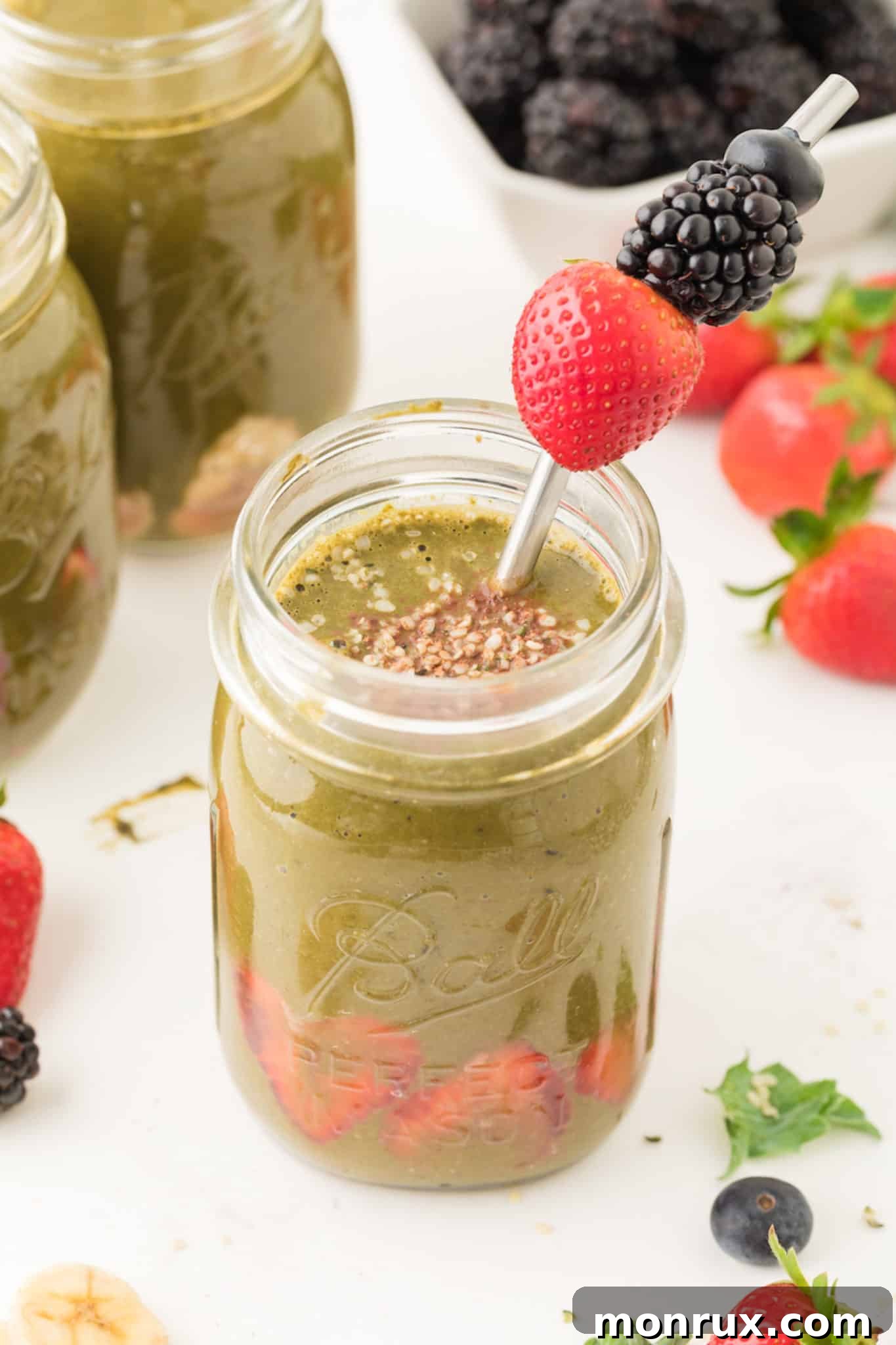 Weight loss green smoothie served in a ball jar with a berry skewer.