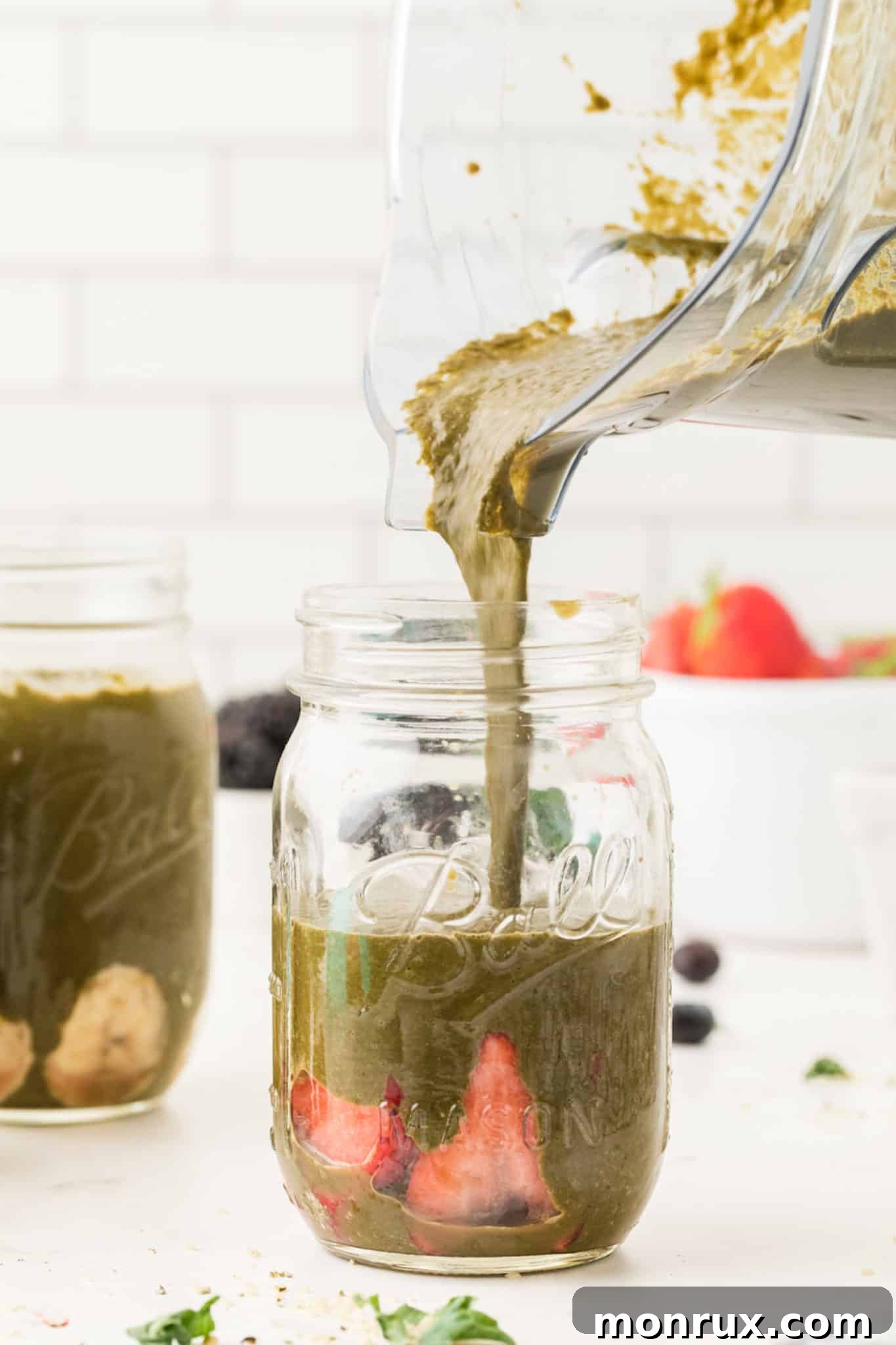 photo showing pouring a green smoothie into a jar.