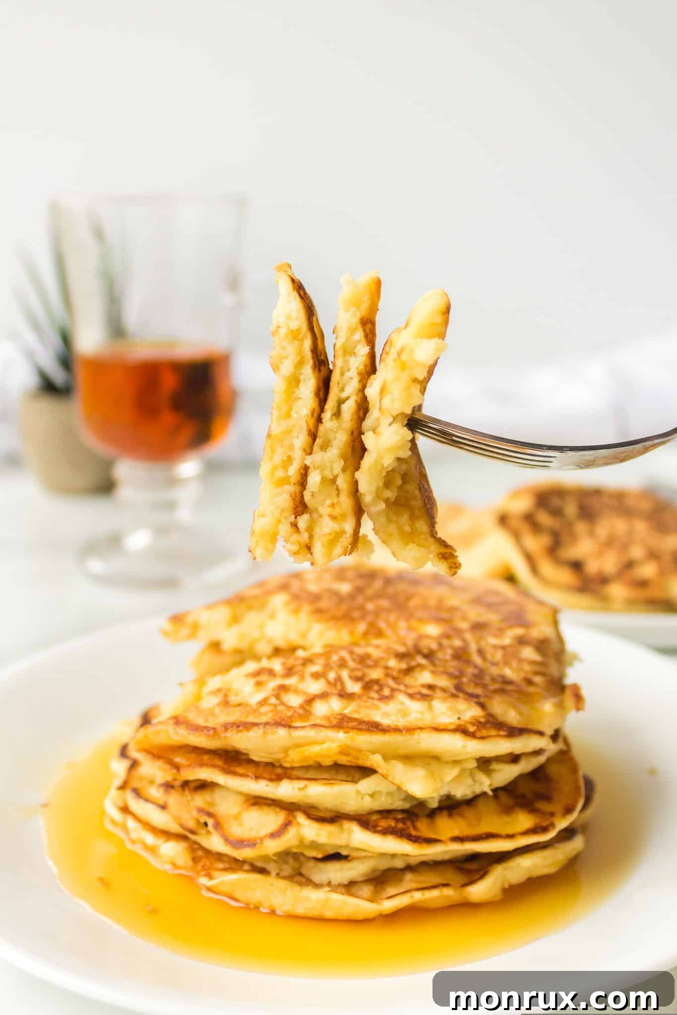 A close-up of a fork piercing a fluffy coconut milk pancake, showcasing its tender texture.