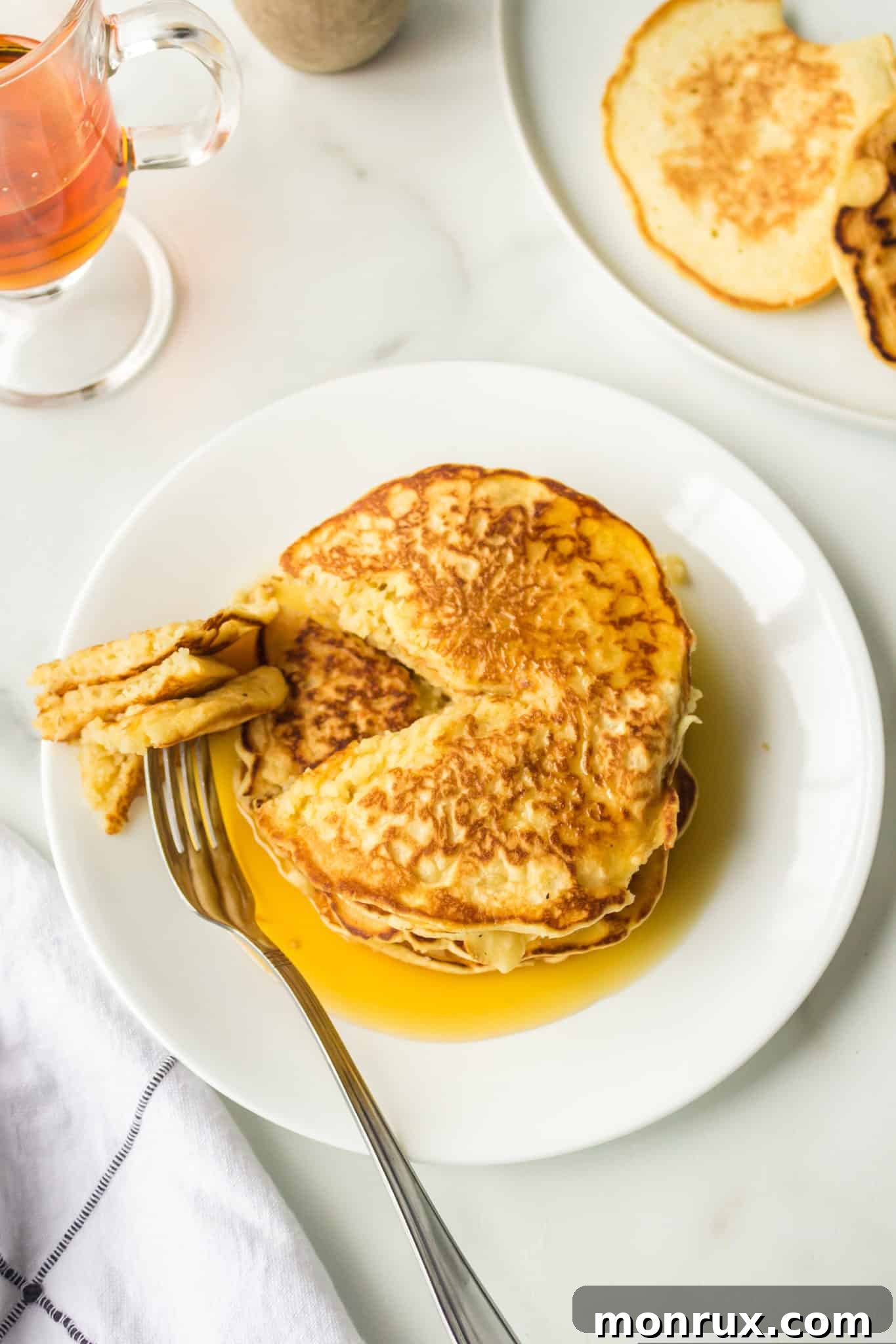 A plate of coconut milk pancakes with a fork, ready to be eaten.