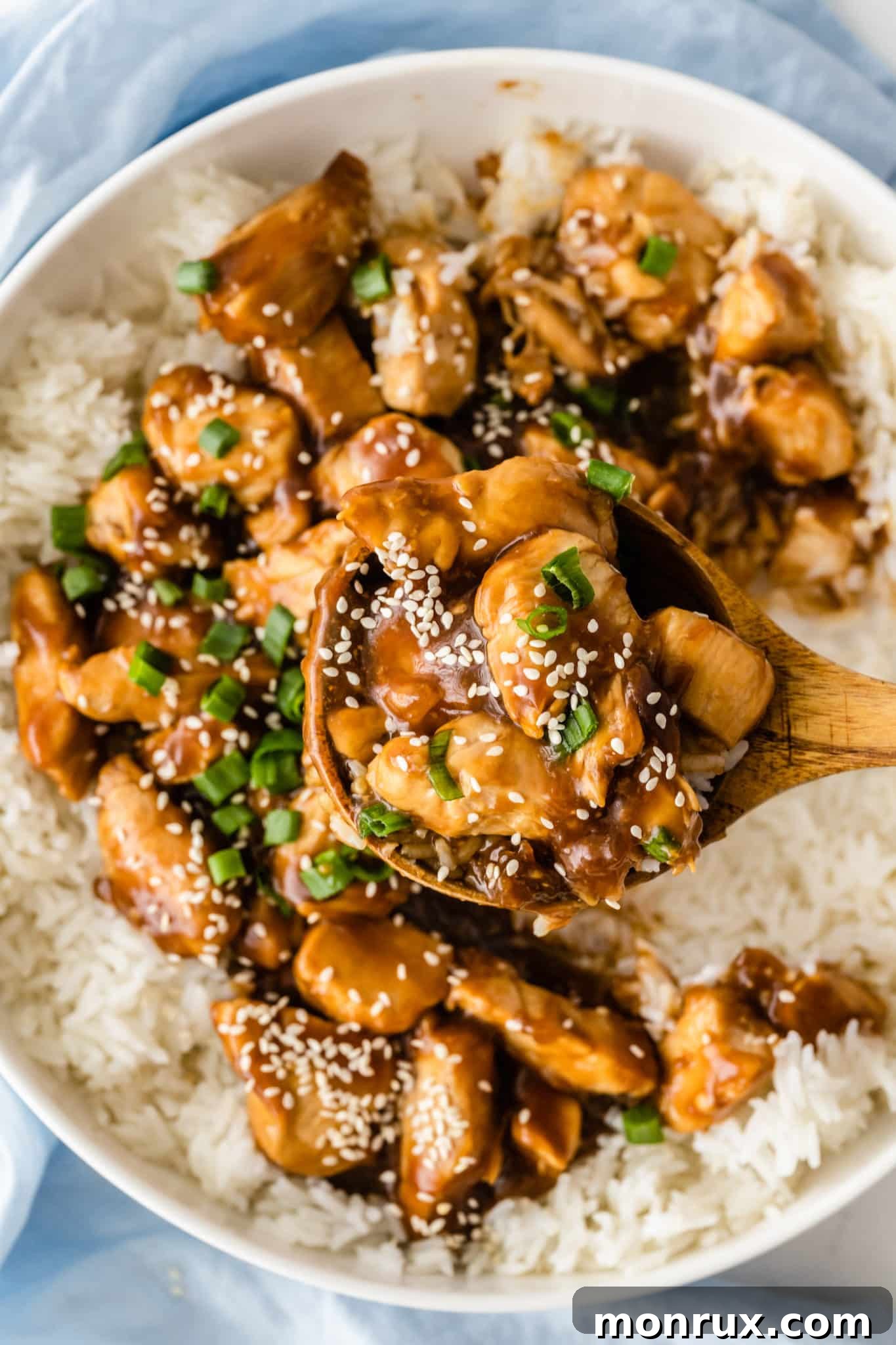 Teriyaki chicken served in a bowl over steamed rice, garnished with green onions and sesame seeds
