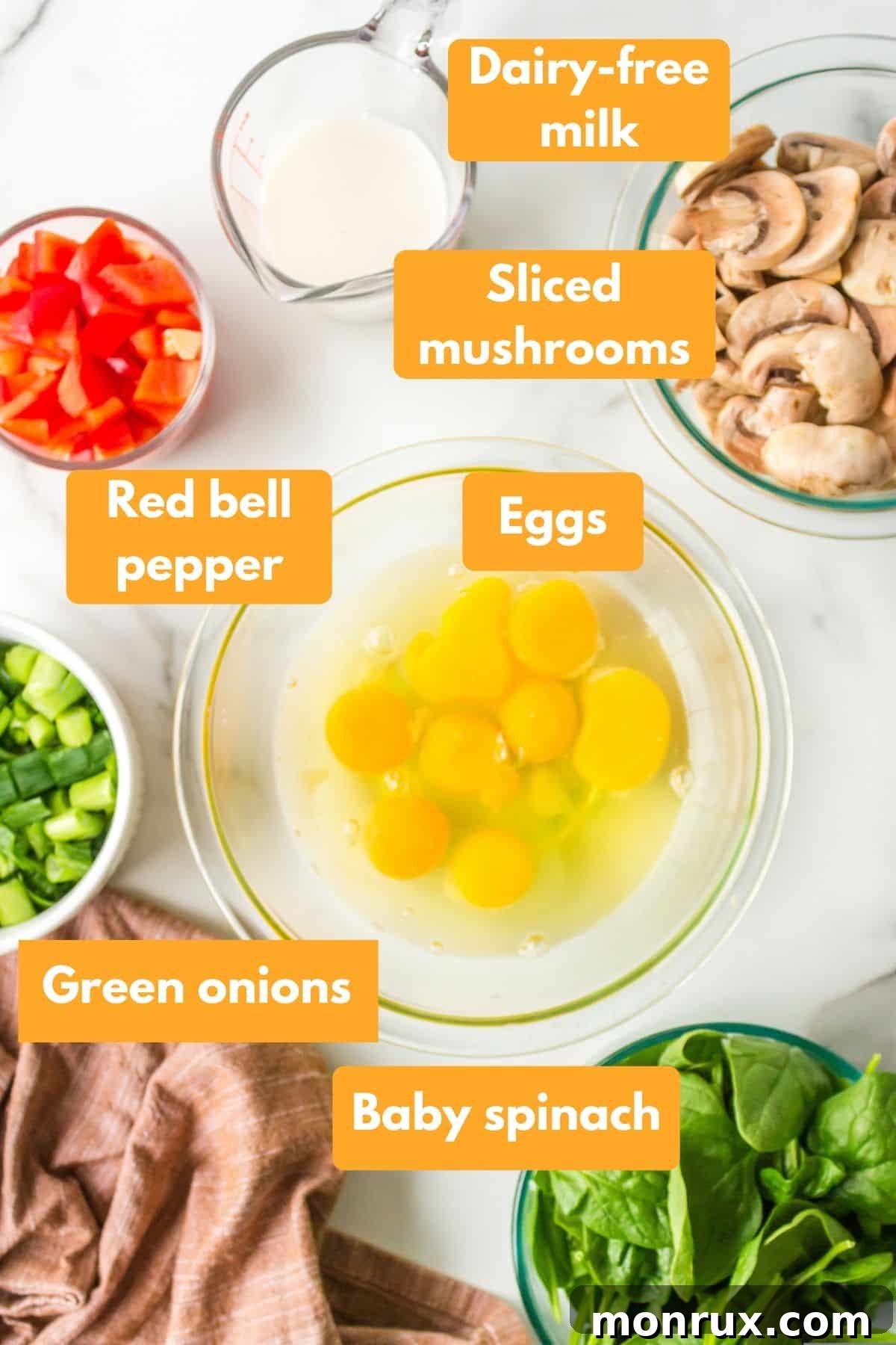 Fresh ingredients laid out for a gluten-free vegetable frittata, including bell peppers, spinach, mushrooms, and eggs.