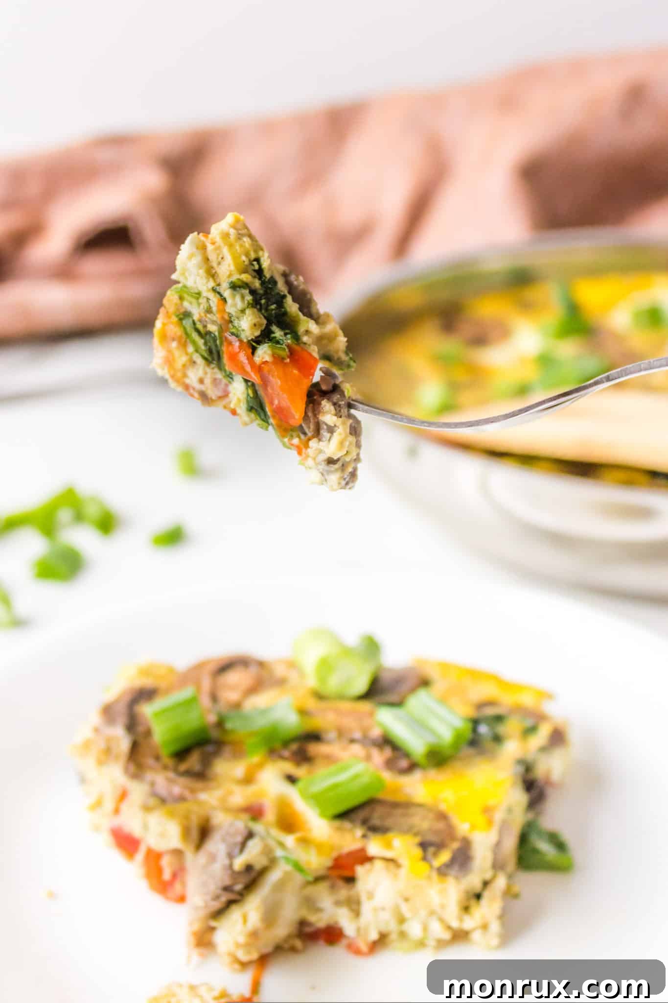 A fork holding a perfect bite of gluten-free and dairy-free frittata, showing the fluffy egg and vegetable texture.