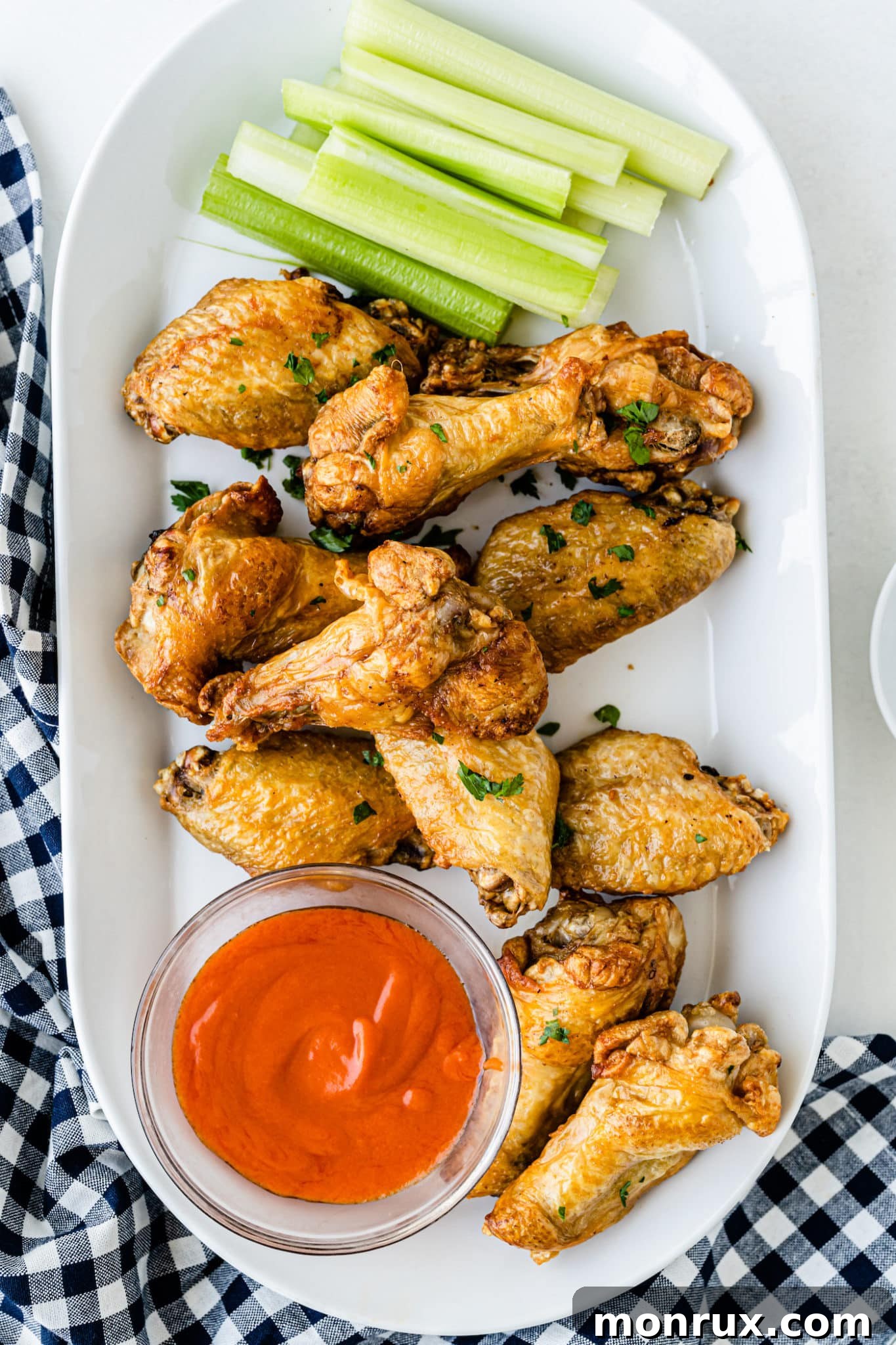 Air fryer frozen chicken wings served with buffalo sauce and celery sticks.