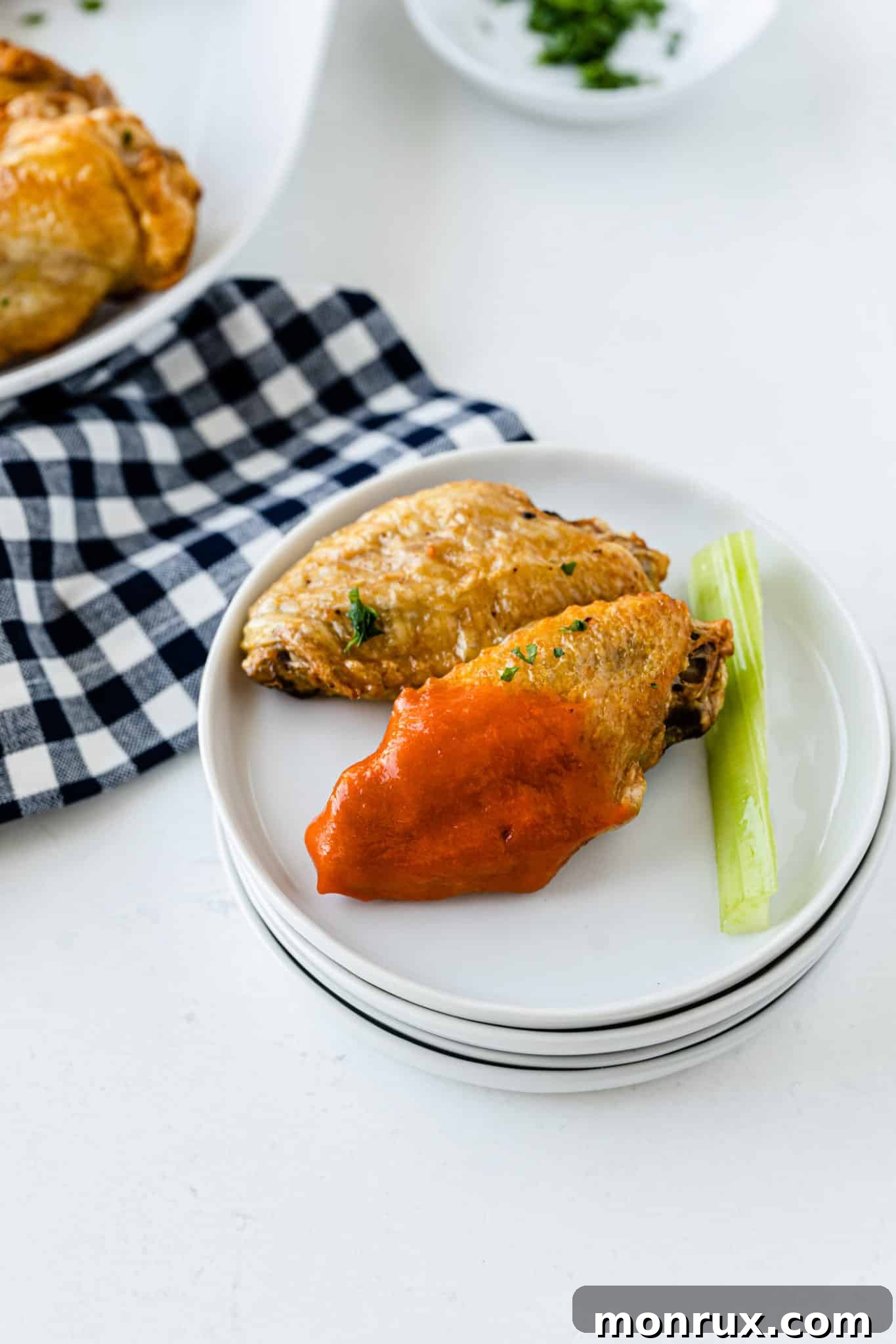 Air fryer frozen chicken wings served with buffalo sauce and celery sticks on a wooden board.
