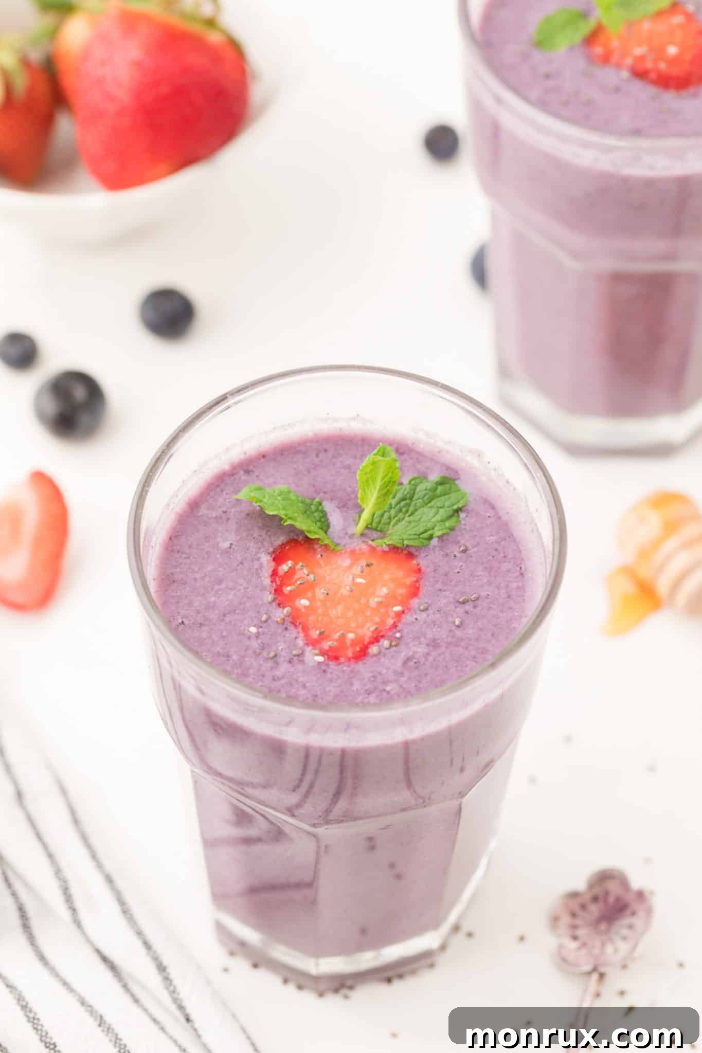 A vibrant strawberry blueberry smoothie in a tall glass, garnished with fresh berries.