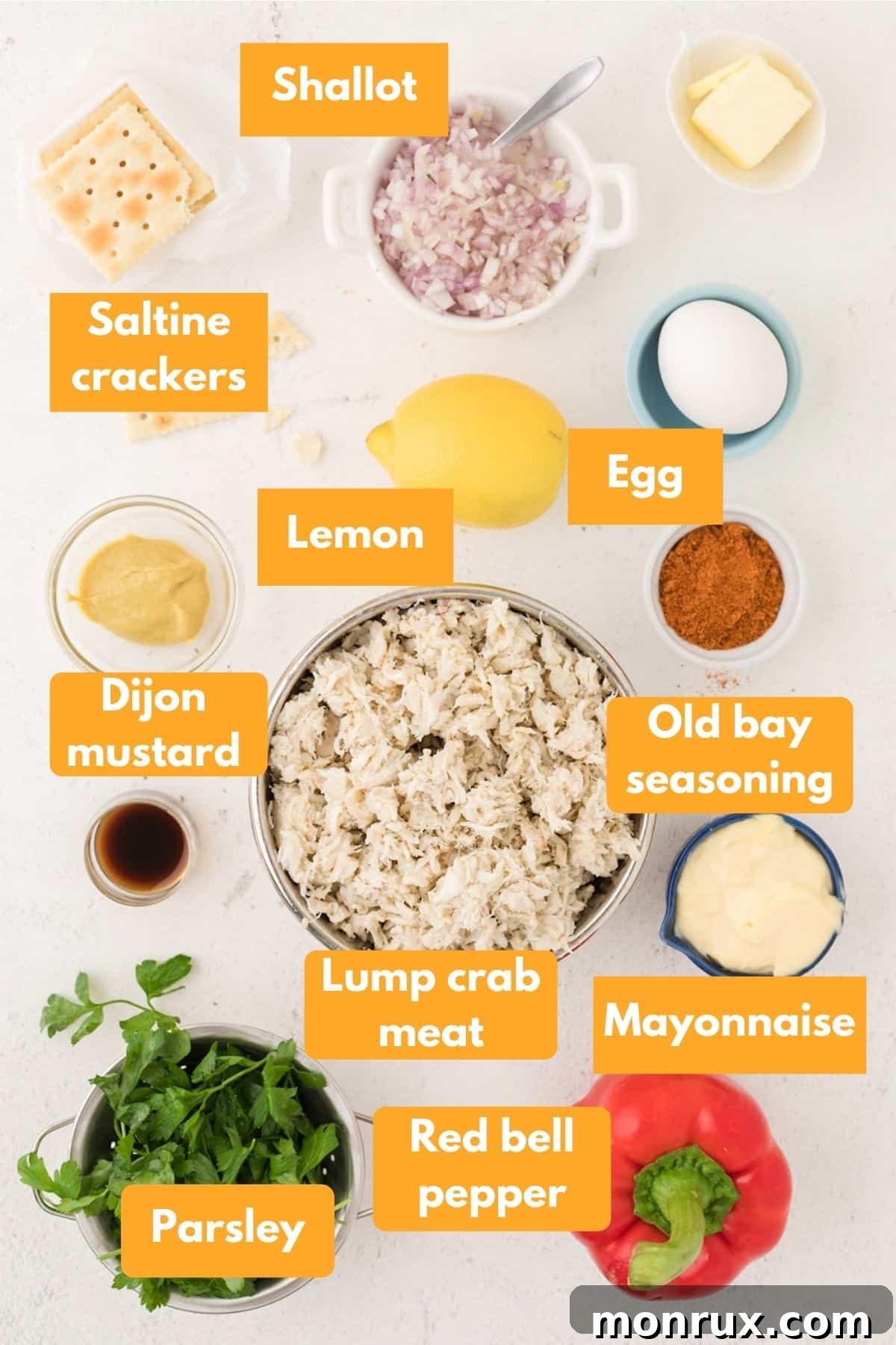 A selection of fresh ingredients laid out for making crab cakes, including lump crab meat, bell peppers, and seasonings.