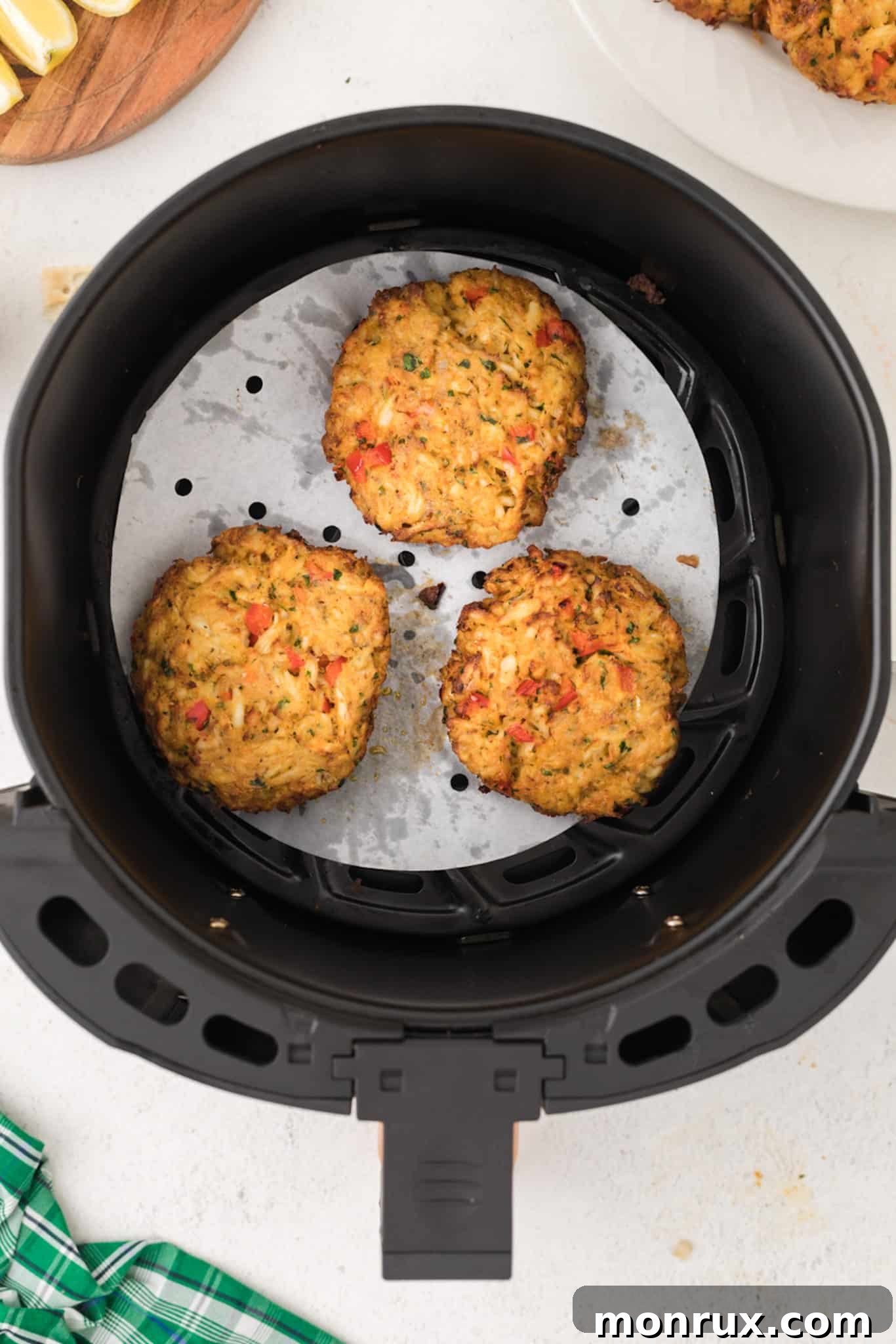 A close-up of cooked crab cakes nestled in an air fryer basket, showcasing their crispy texture.