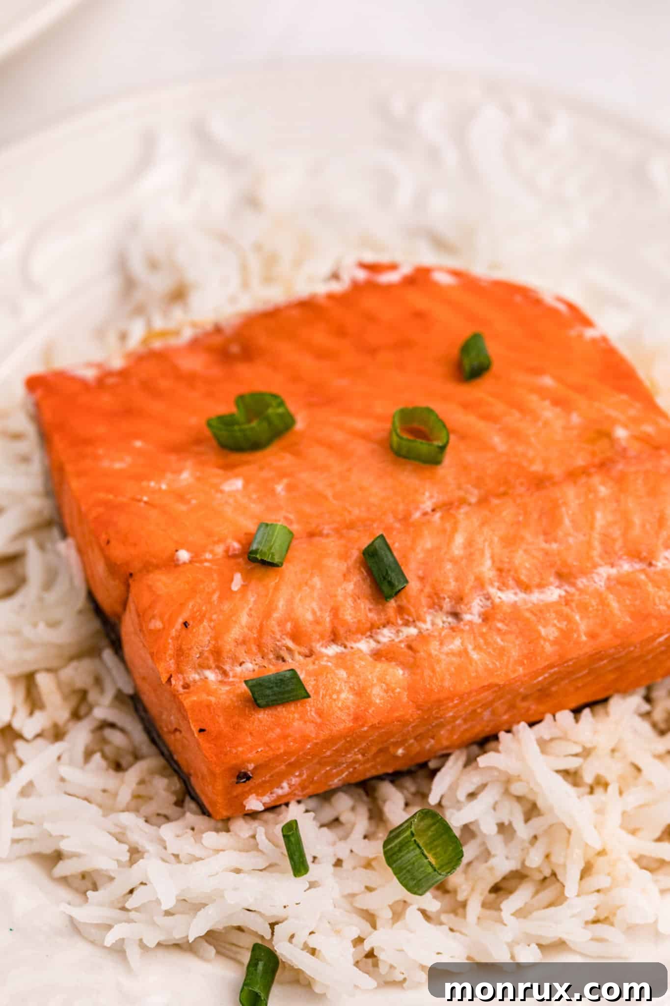Instant Pot salmon with rice served on a plate, garnished with fresh green onions and sesame seeds.