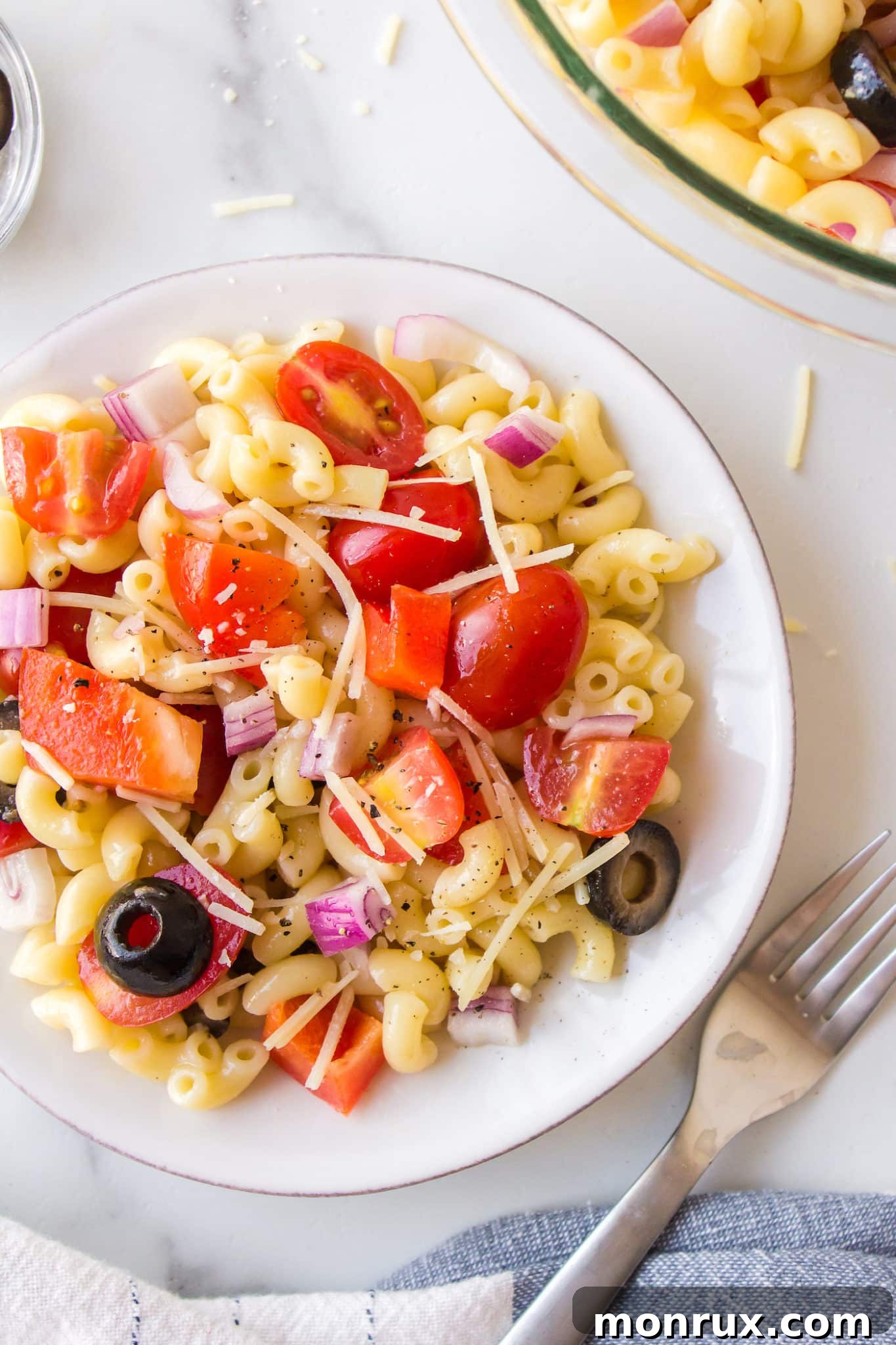 A small serving of gluten-free veggie pasta salad on a small white plate, garnished with fresh herbs and a drizzle of olive oil.