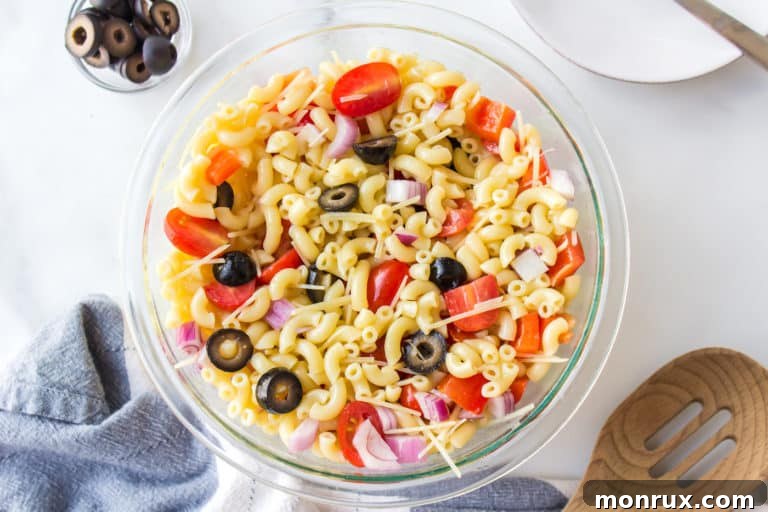 Gluten free pasta salad with tomatoes and peppers in a glass bowl.