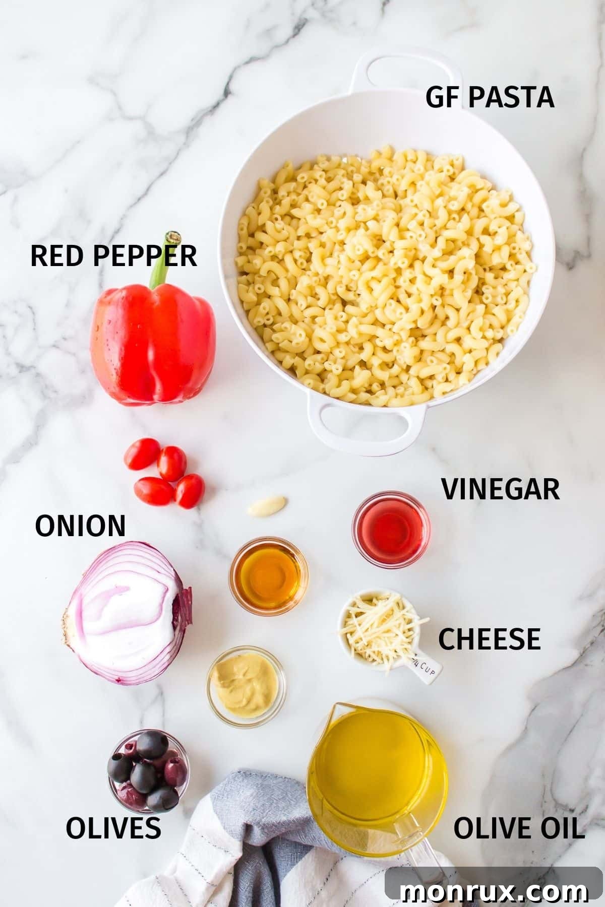 Assortment of fresh ingredients for pasta salad, including bell peppers, tomatoes, onions, olives, and a bottle of olive oil, neatly arranged in small bowls on a clean white surface.