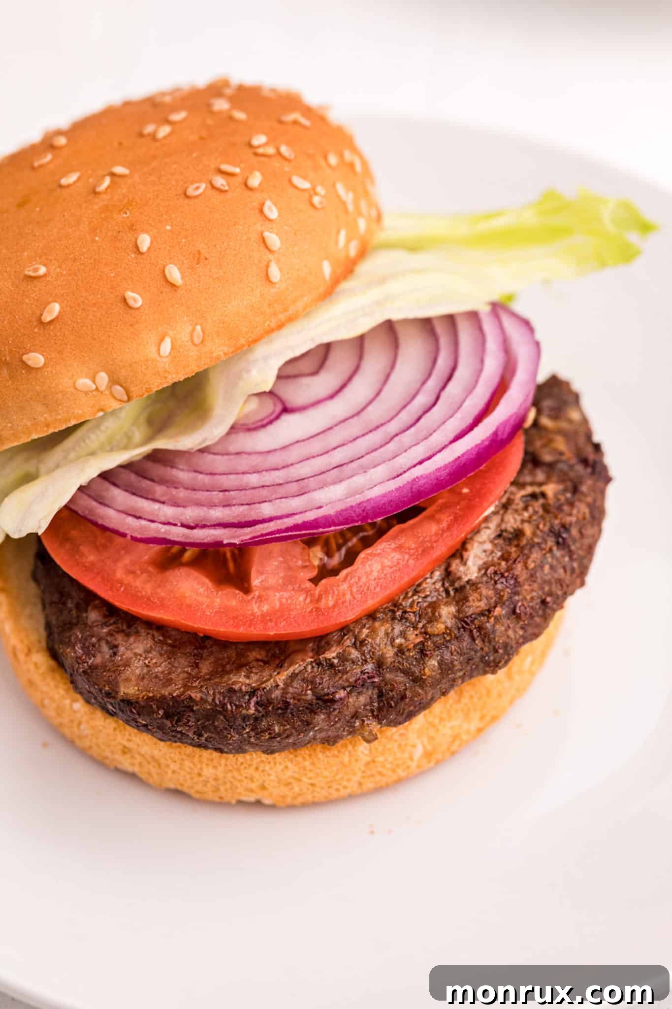A air fryer frozen hamburger with onion and tomato.
