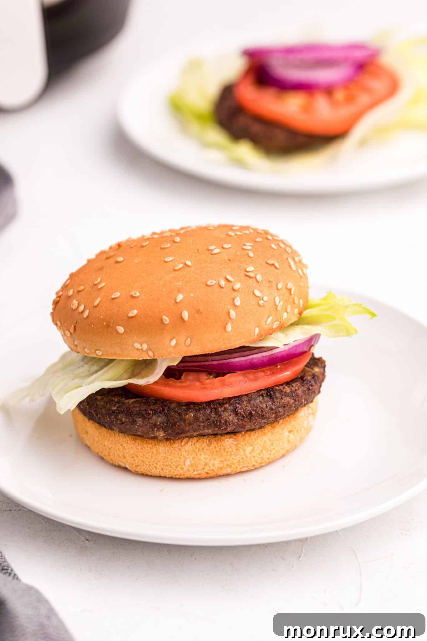 An air fryer cooked hamburger with onion and tomato.