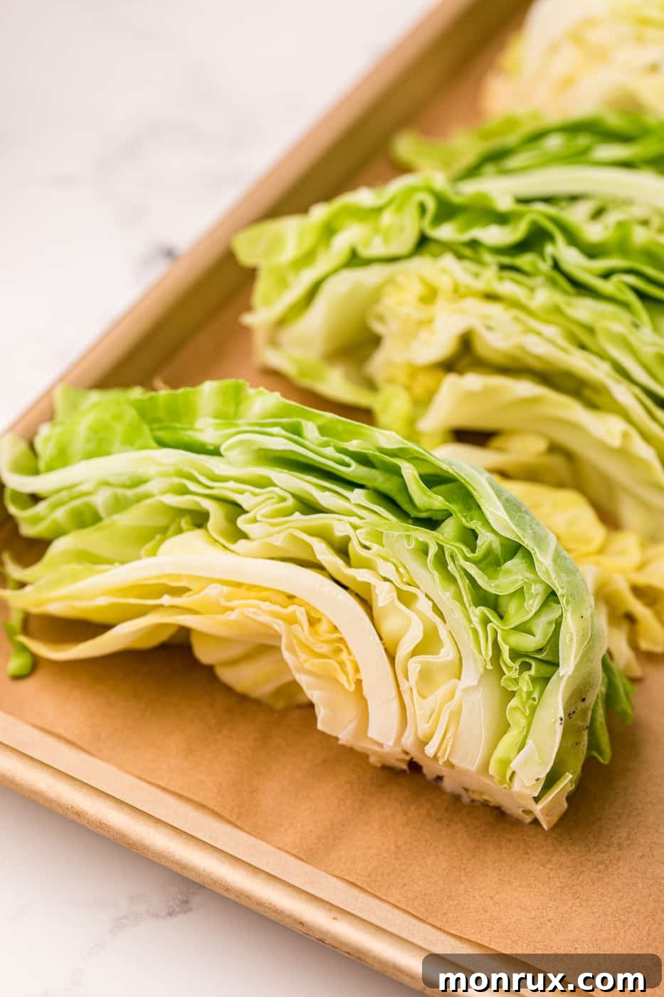 Neatly arranged frozen cabbage slices on a baking sheet, ready for transfer to freezer bags.