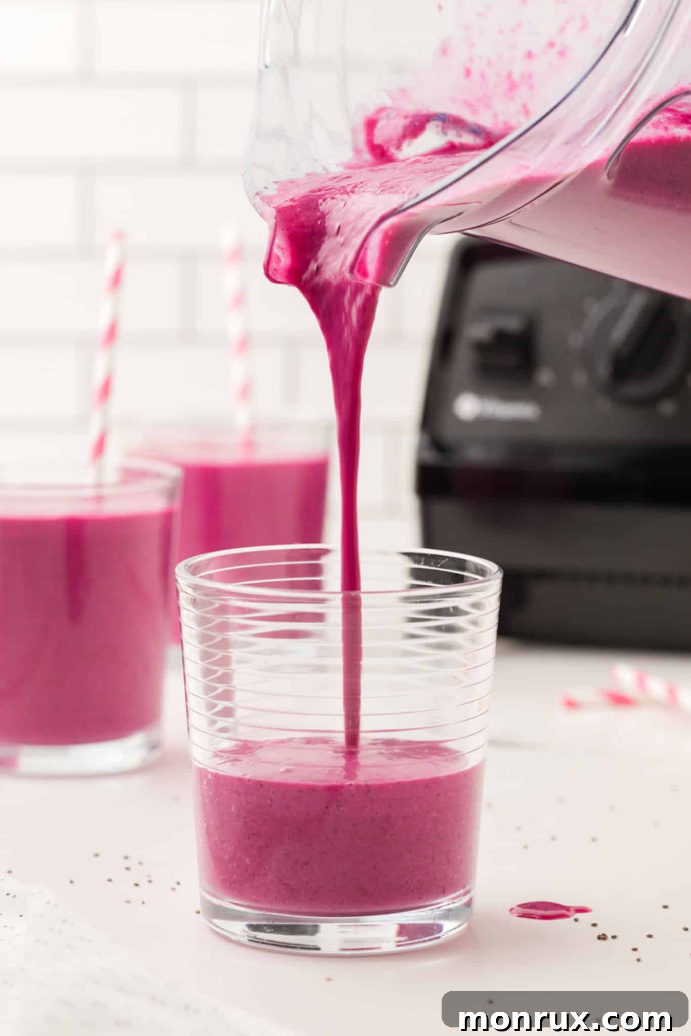 Photo showing the purple dragon fruit banana smoothie being poured into a tall glass, highlighting its smooth texture.