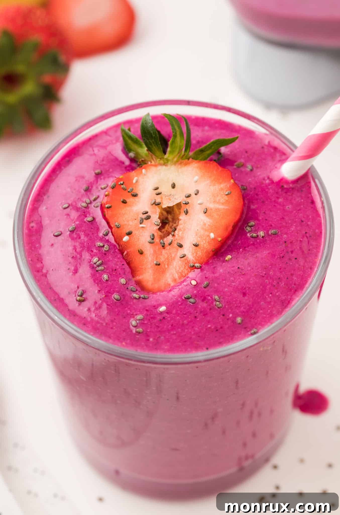 A single glass of purple dragon fruit banana smoothie, garnished with a slice of fresh dragon fruit and a pink striped straw.