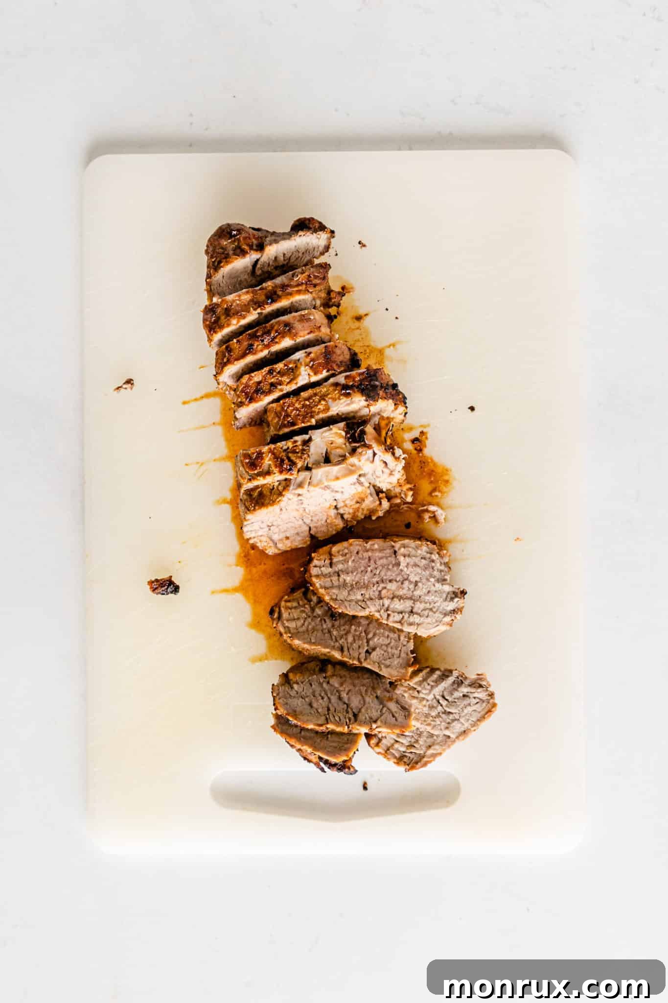 A perfectly sliced air-fried pork loin on a cutting board, ready for serving.