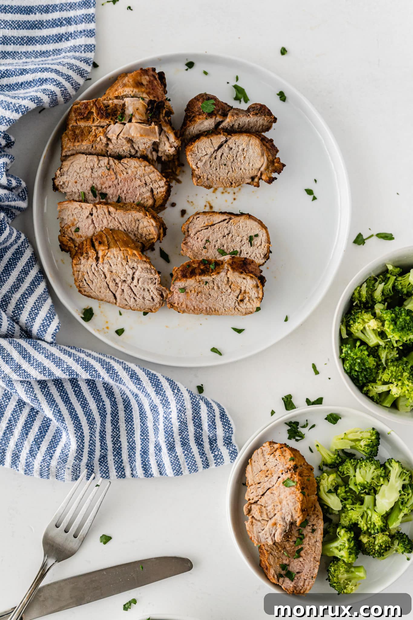 Air fryer pork loin served with a side of steamed broccoli on white plates, showcasing a healthy meal.