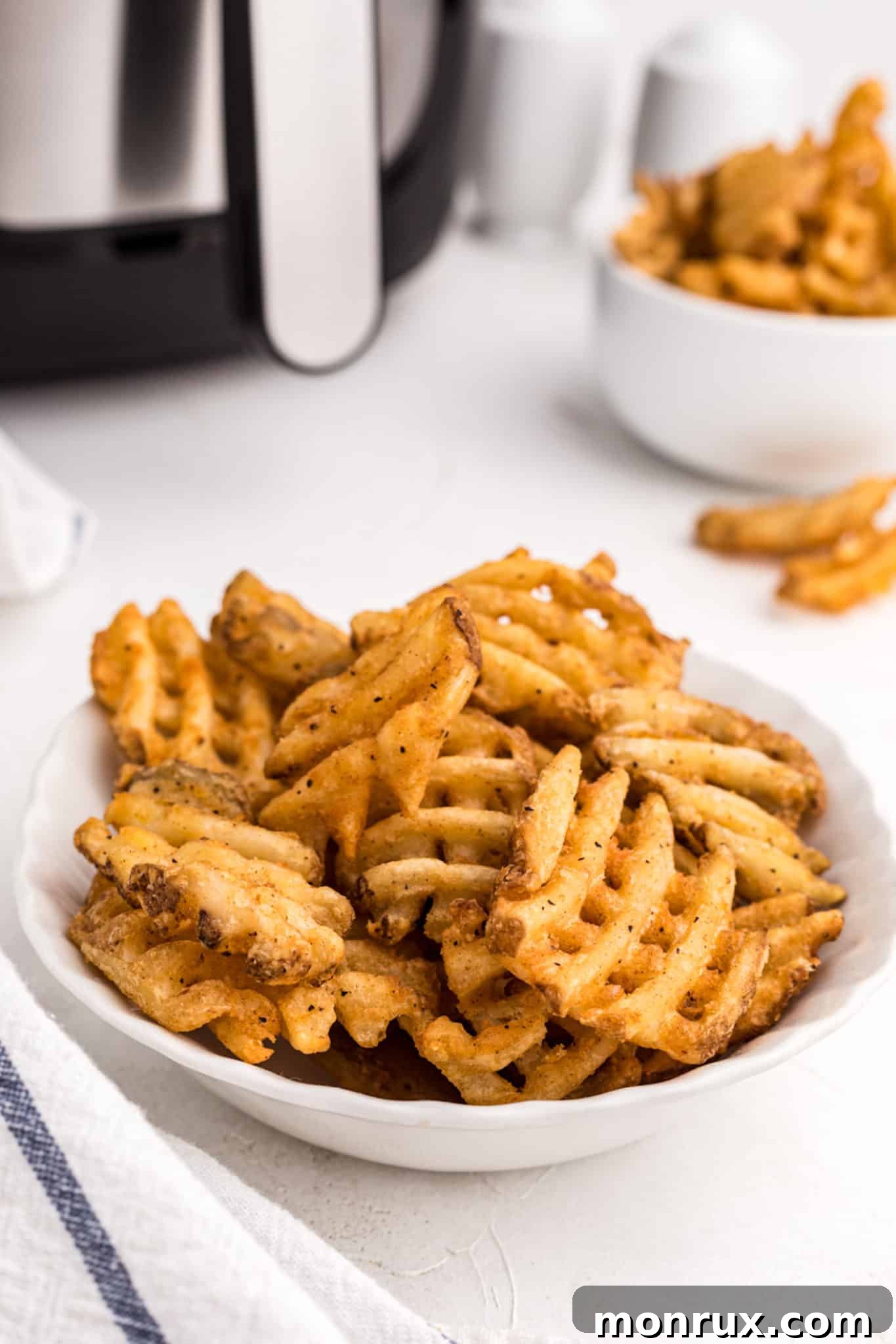 A bowl of perfectly air-fried golden waffle fries, seasoned and ready to be enjoyed as a snack or side dish.