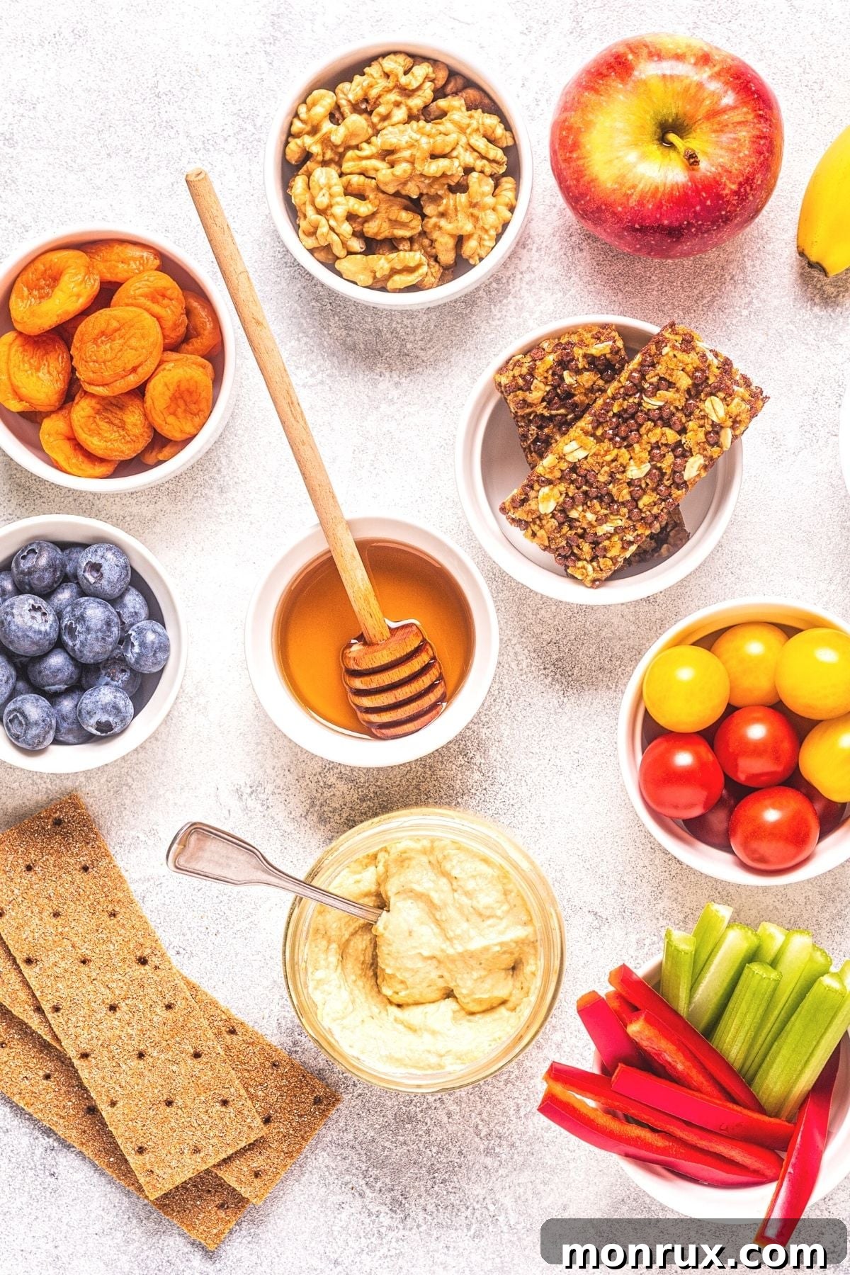 An array of colorful healthy gluten-free and dairy-free snacks laid out on a table, including fruits, vegetables, nuts, and dips.