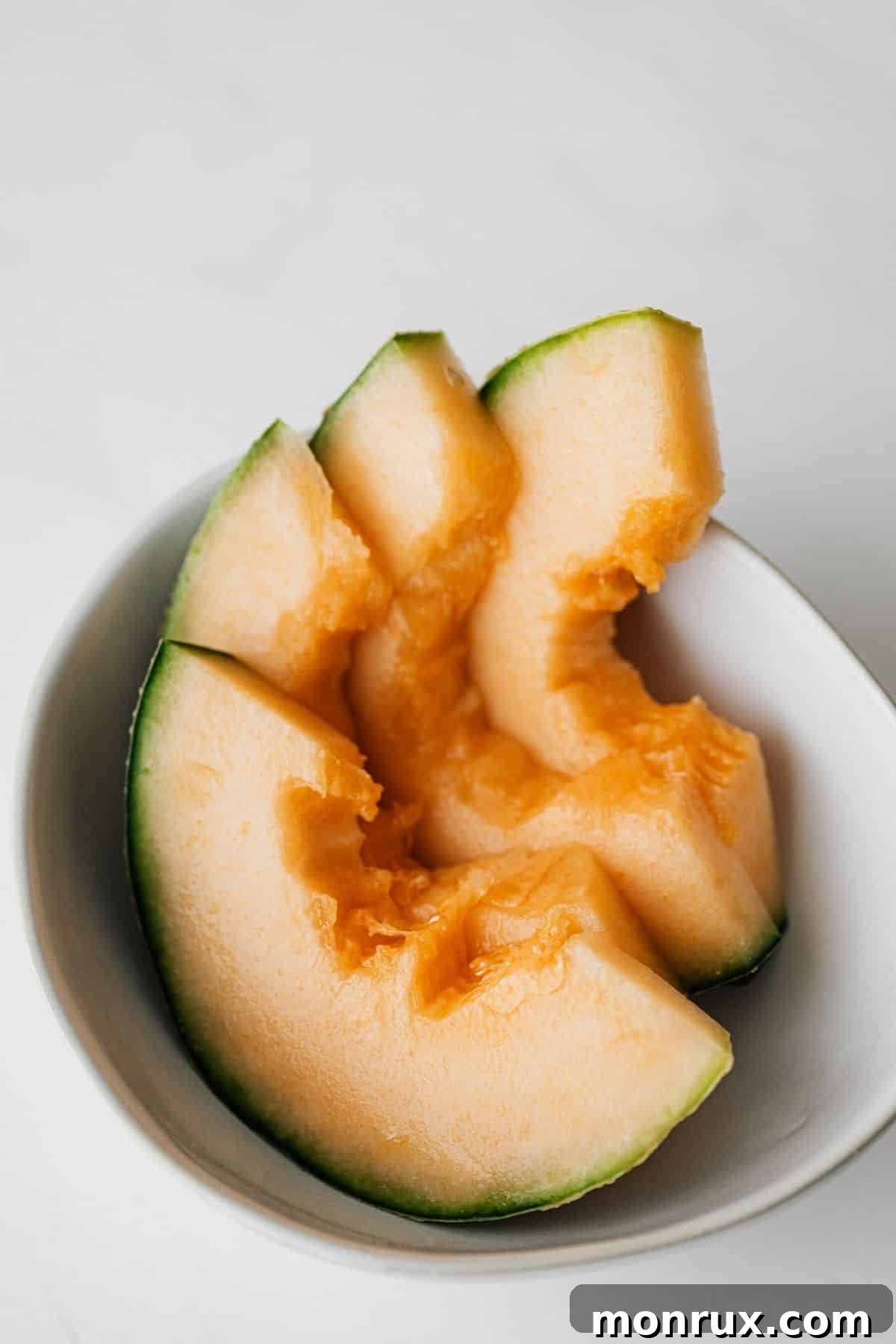 Bright orange cantaloupe slices artfully arranged in a bowl, showcasing its refreshing and juicy appeal.