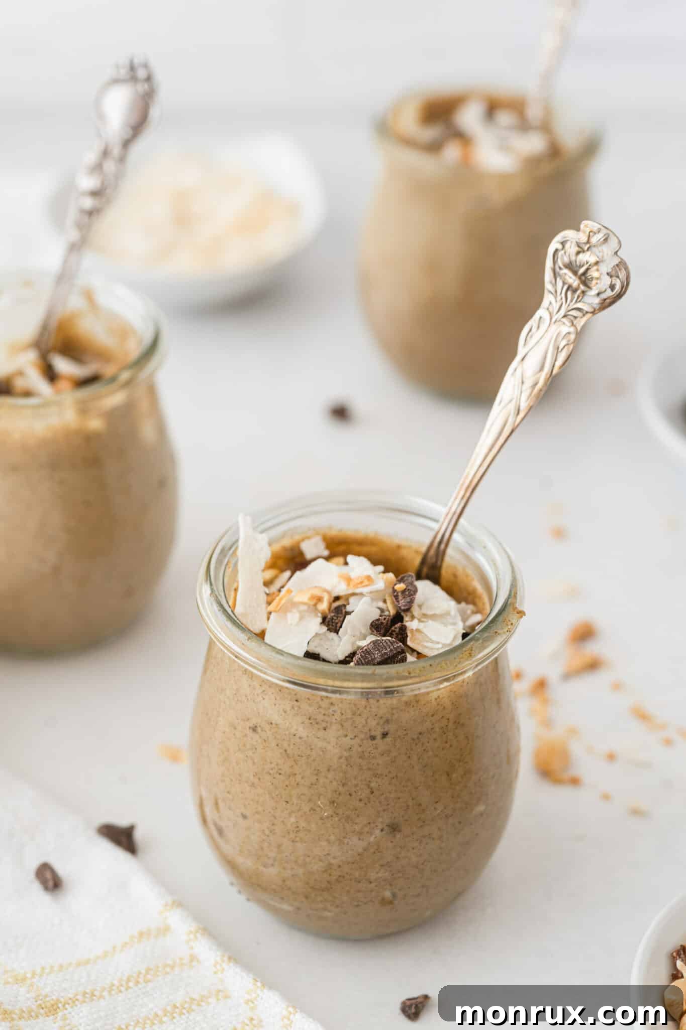 Small glass jars of delicious peanut butter chia pudding, beautifully topped with chocolate shavings and shredded coconut.