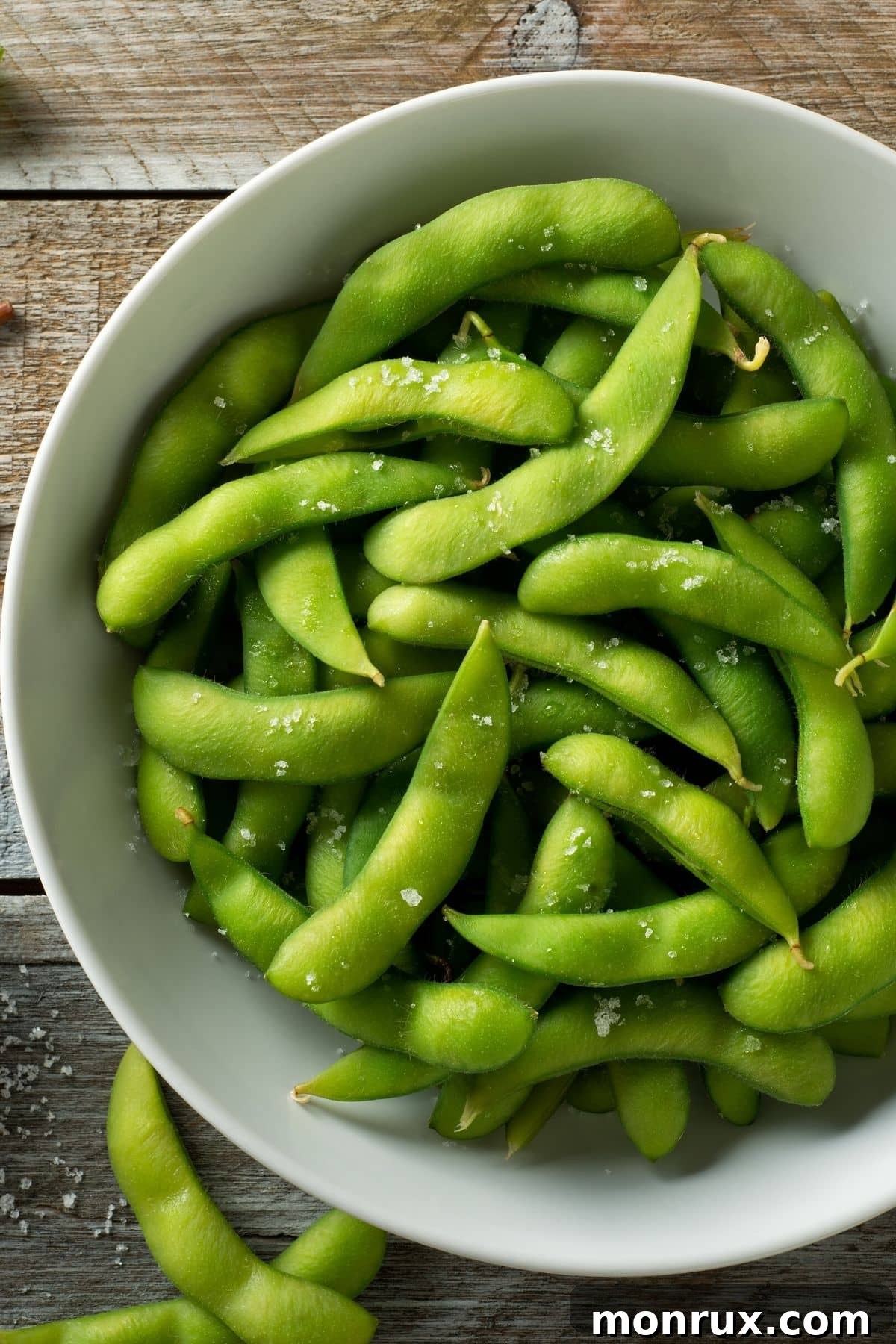 A bowl of vibrant green edamame pods resting on a rustic wooden table, ready to be enjoyed as a healthy snack.