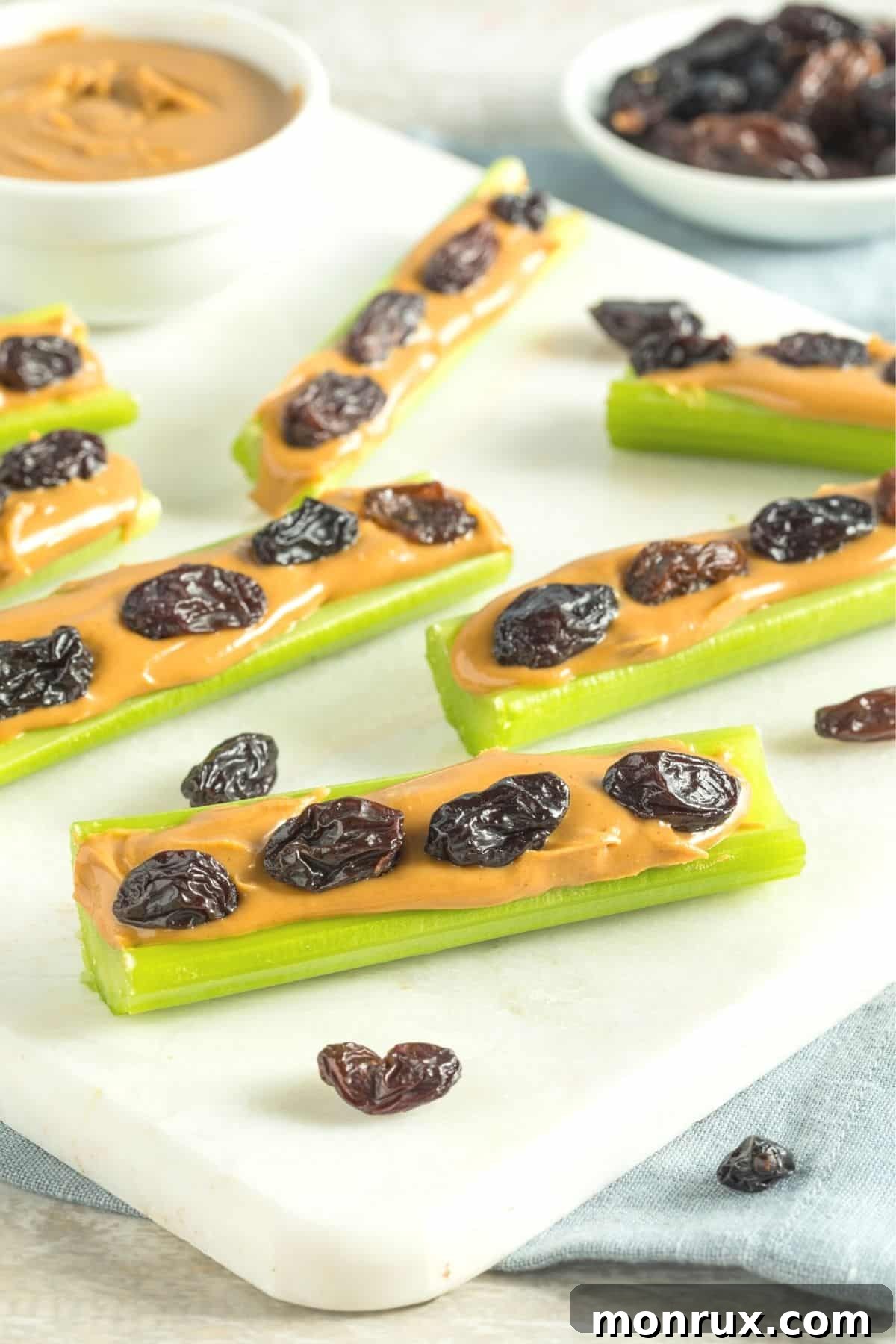 A creative and healthy snack of celery sticks filled with peanut butter and topped with raisins, arranged like 'ants on a log'.