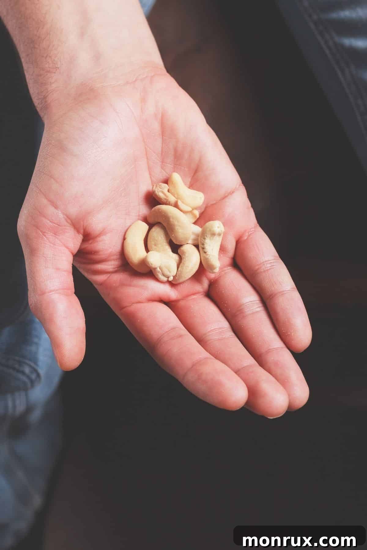 A person gently holding a small handful of assorted nuts, highlighting their natural and wholesome appeal.