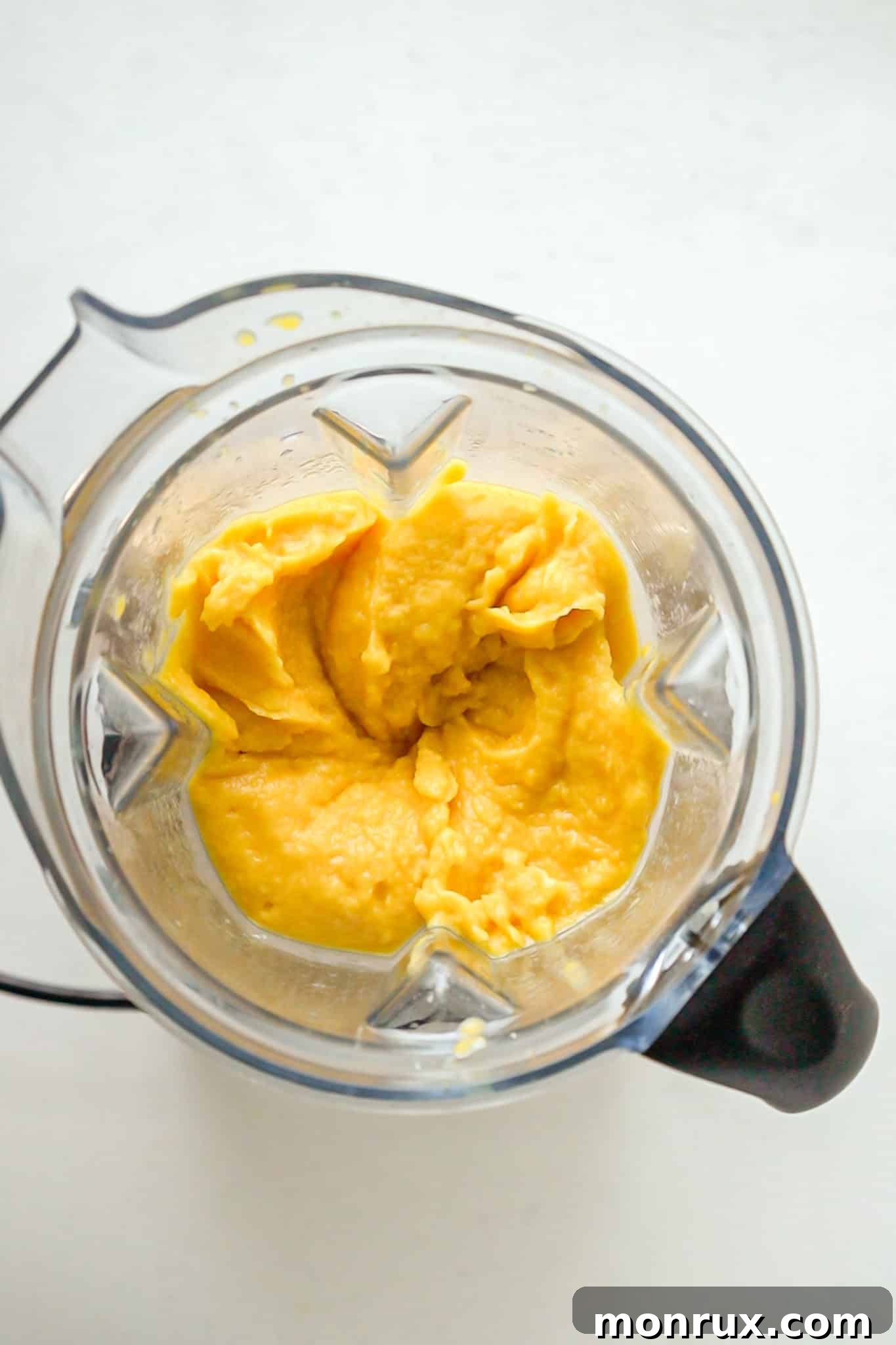 Mango sorbet actively blending in a high-speed blender, with the tamper being used to assist the process.
