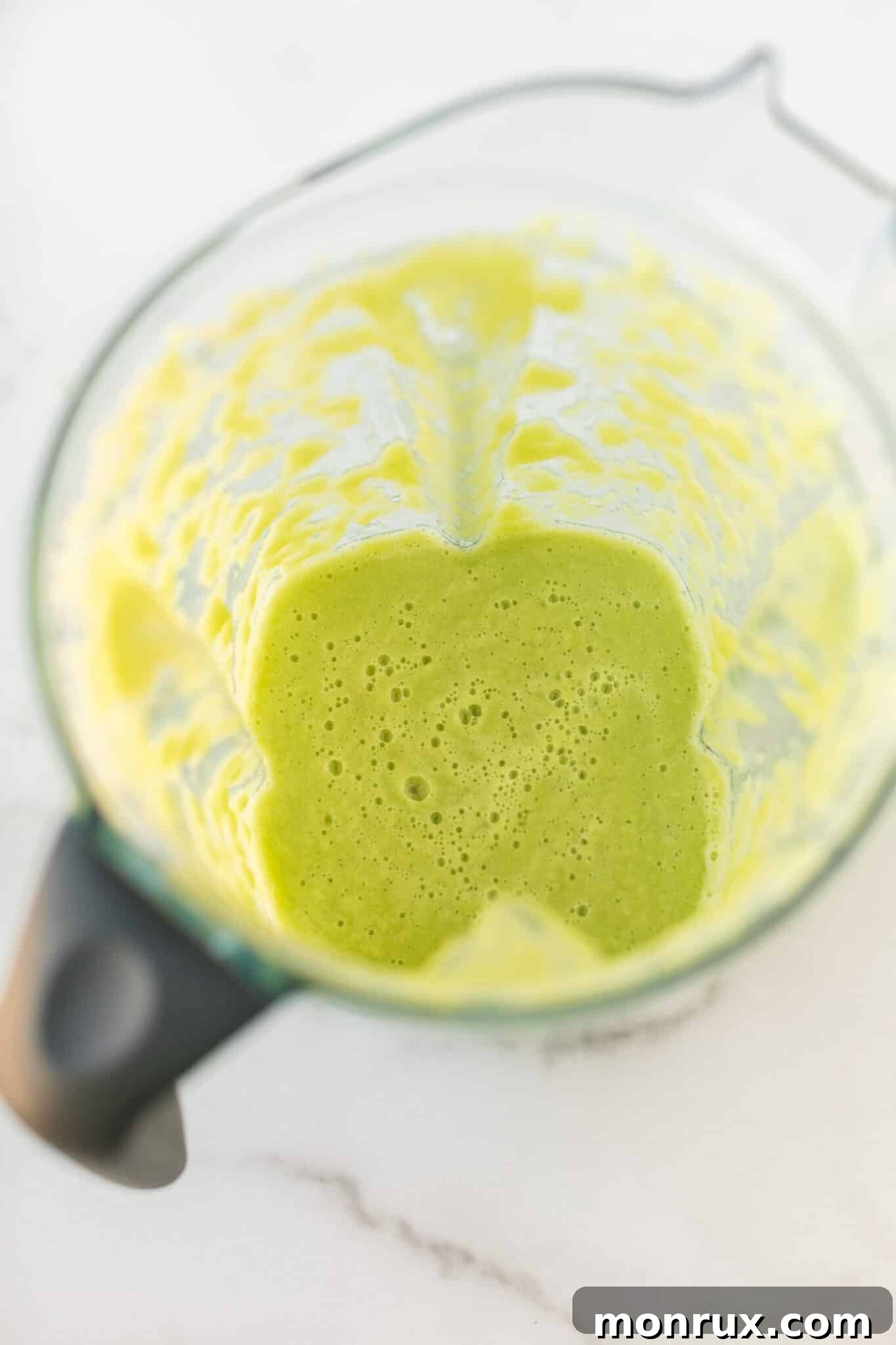 A Vitamix blender filled with smoothly blended green juice, illustrating the powerful processing capabilities of the machine.